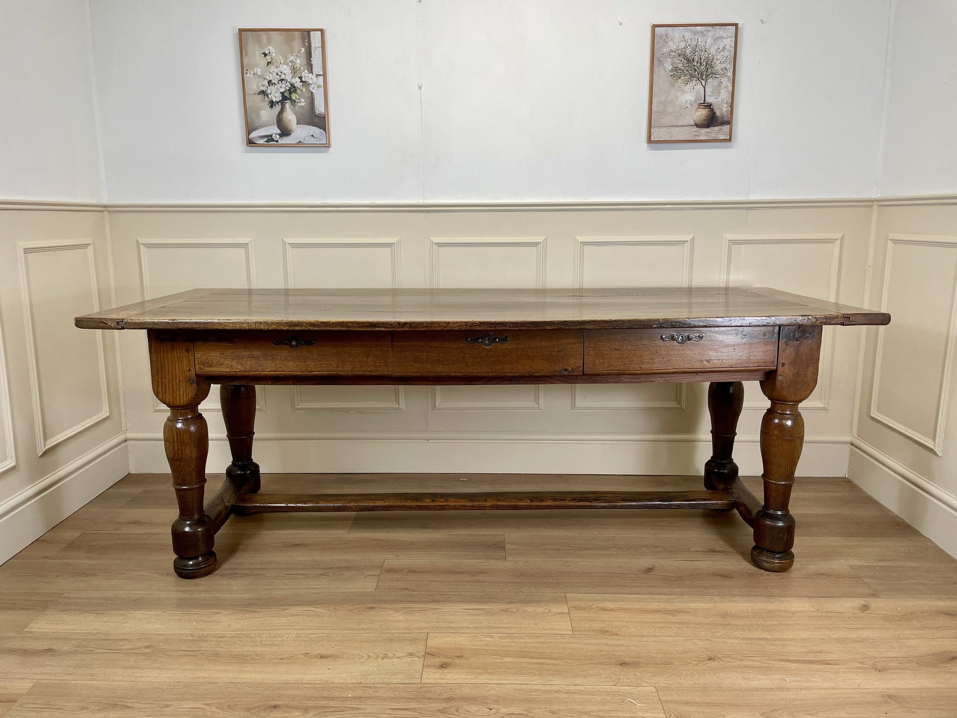 Wooden table in a room with panelled walls and framed pictures.