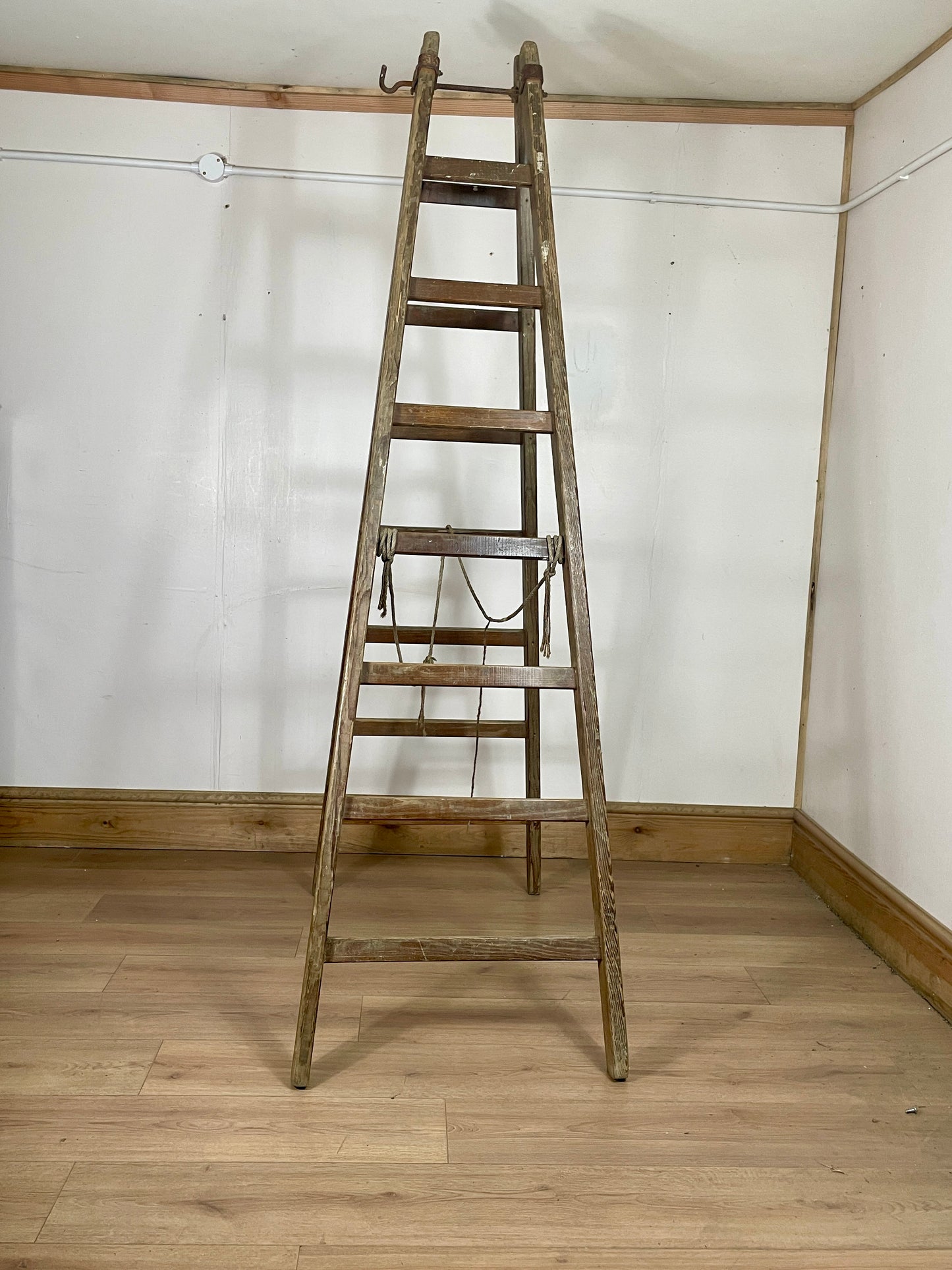 Wooden ladder against a white wall with wooden floor