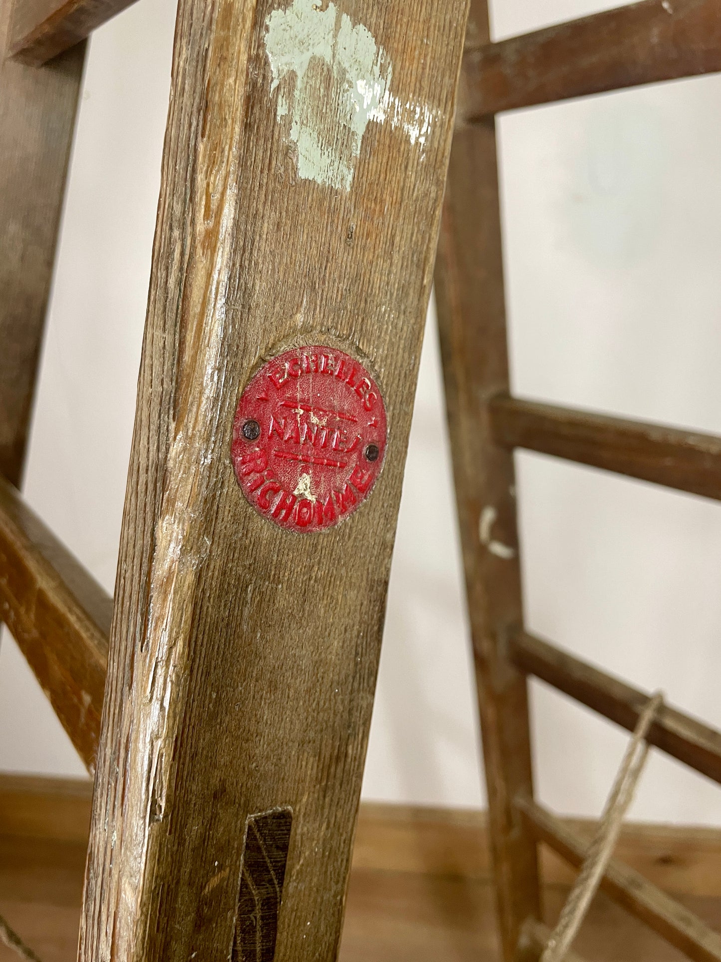 Close-up of a wooden ladder with a red label on a white background