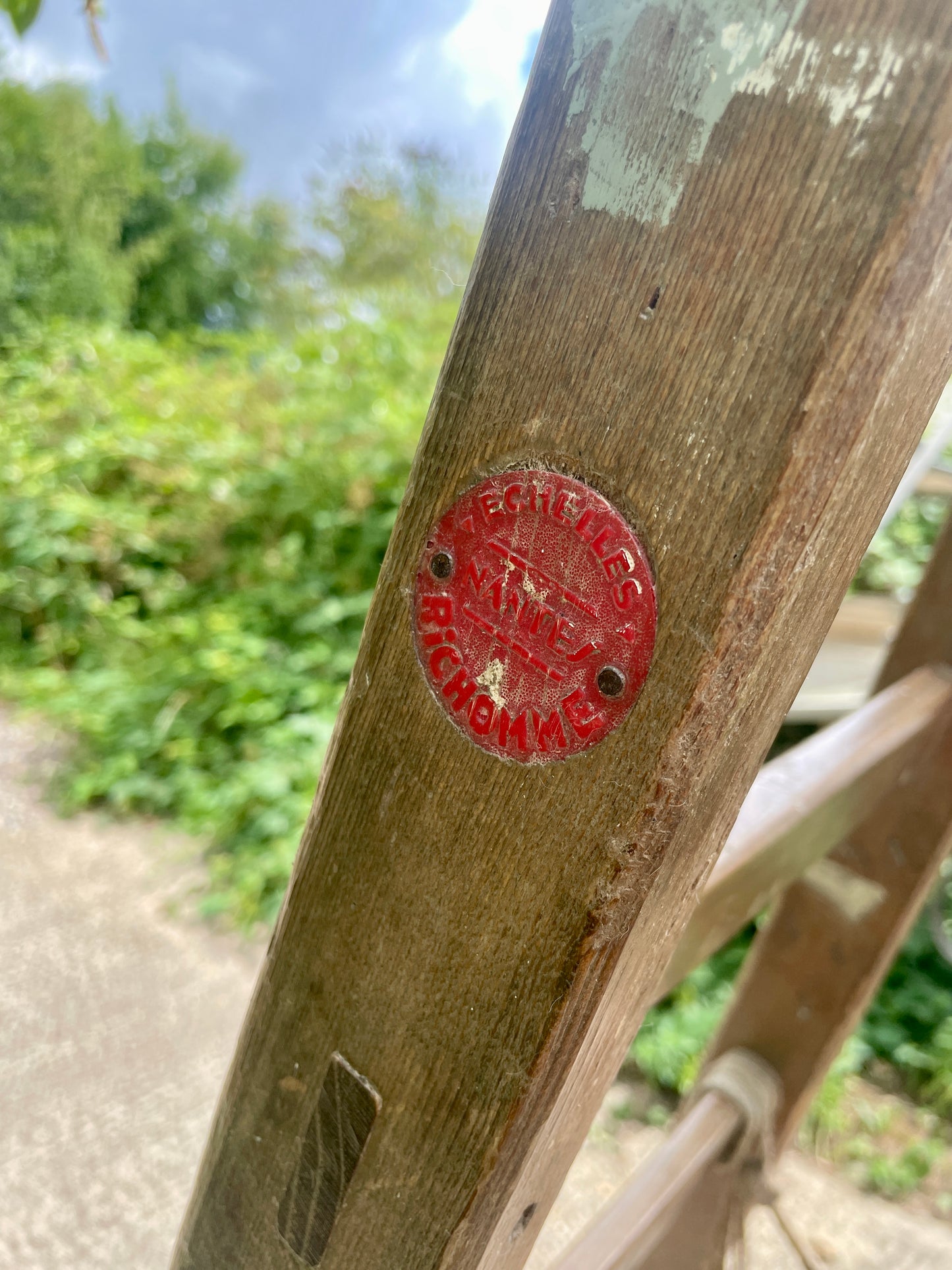Red circular label on a wooden post with blurred greenery in the background