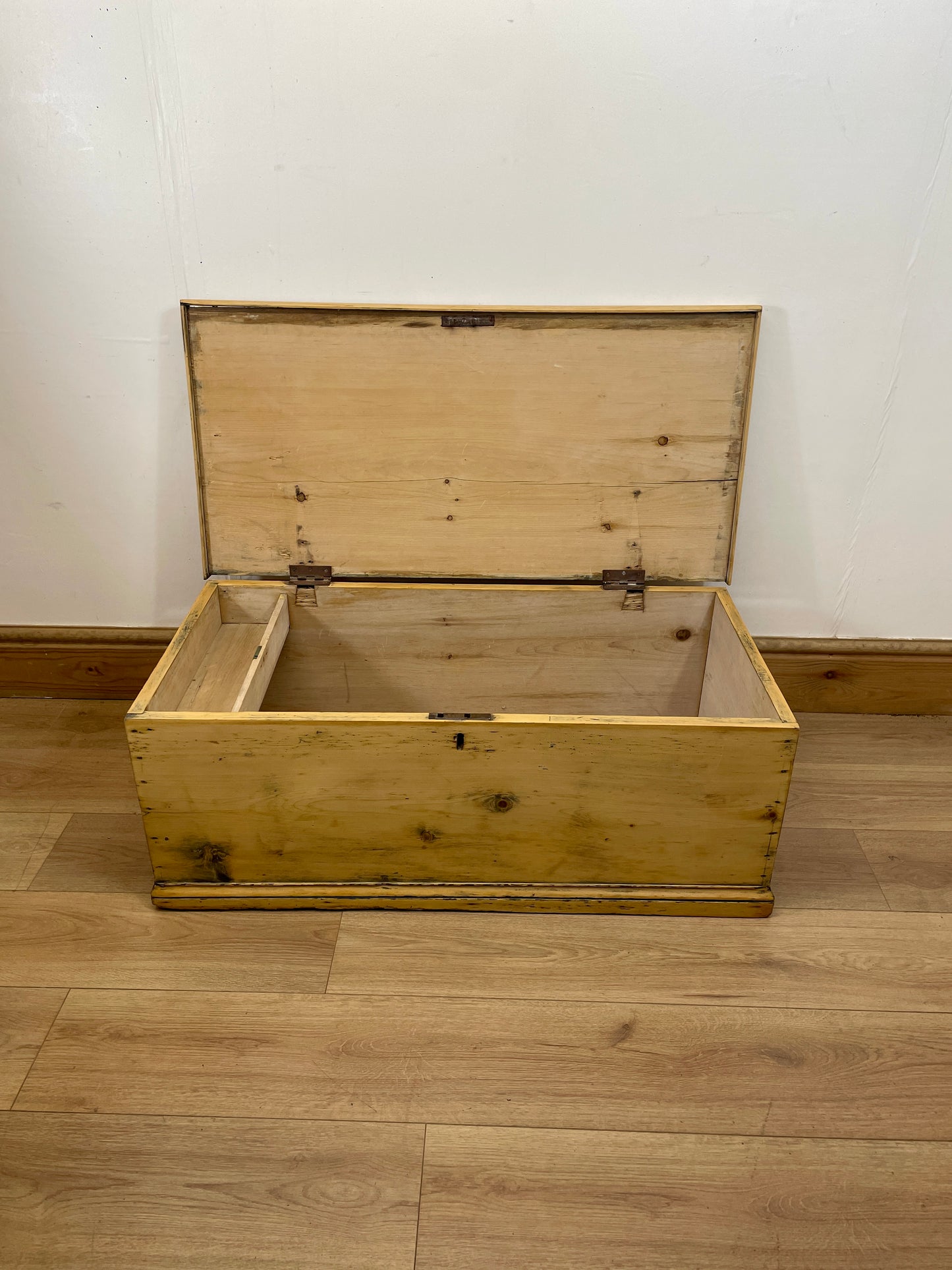 Wooden chest on a wooden floor with a white wall background