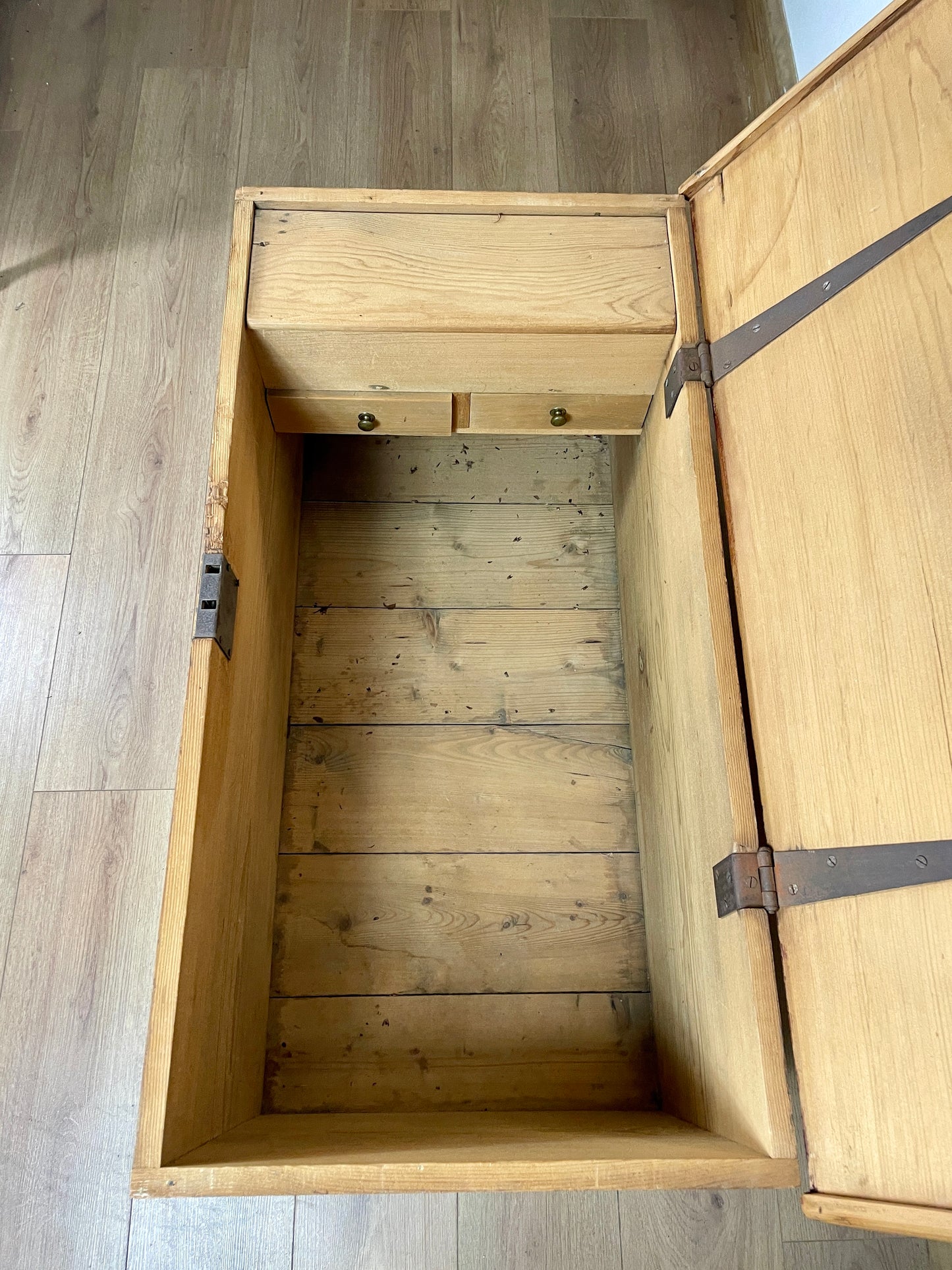 Wooden storage chest with open lid on a wooden floor