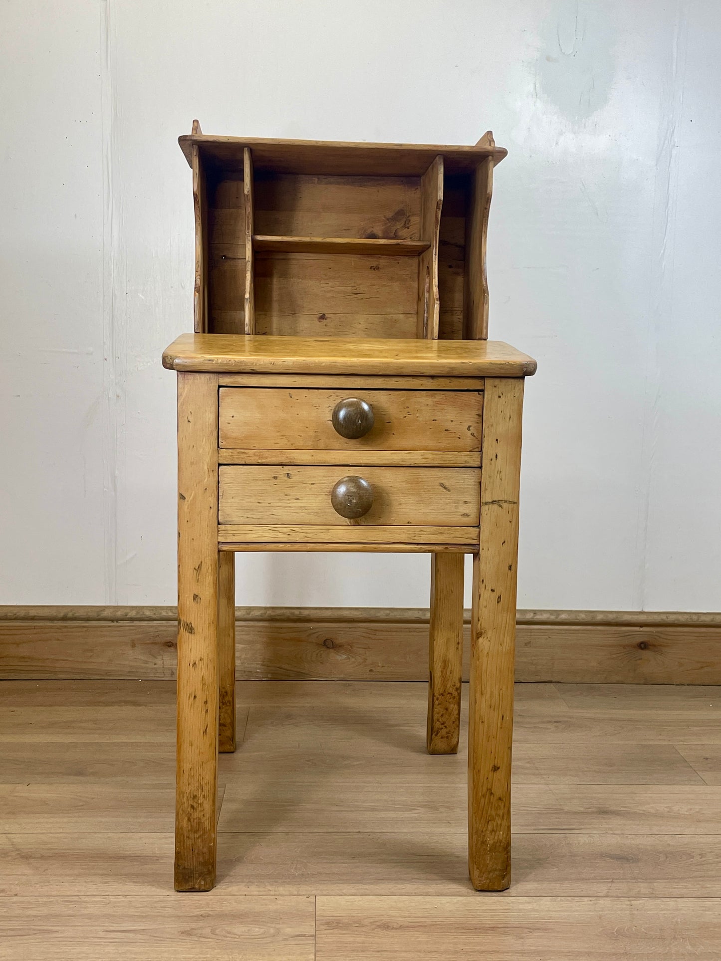 Wooden cabinet with a drawer on a wooden floor against a white wall