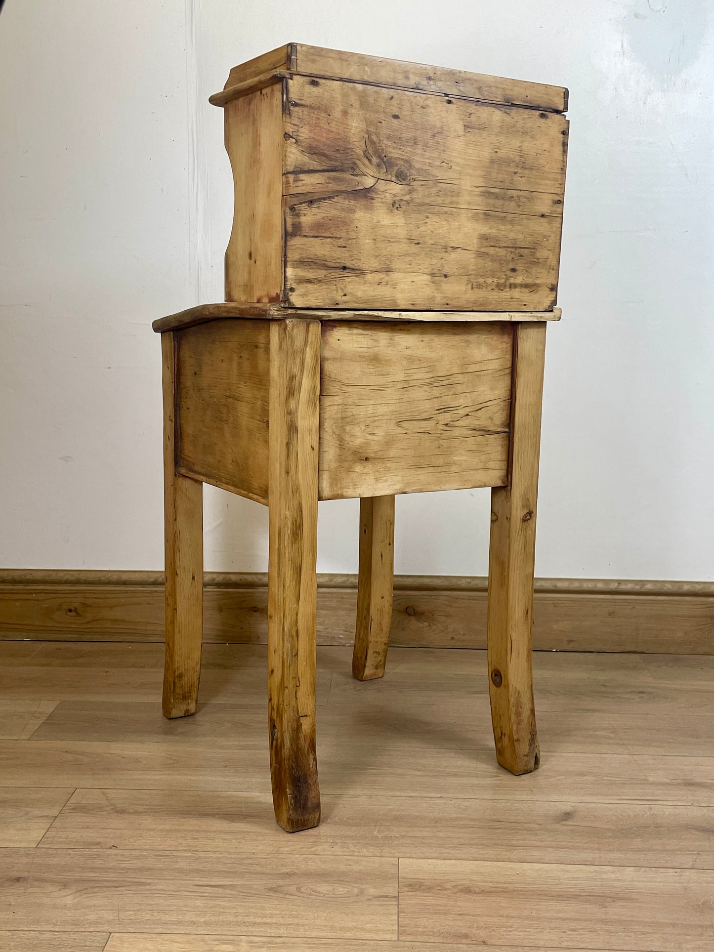 Wooden side table with a drawer against a white wall.