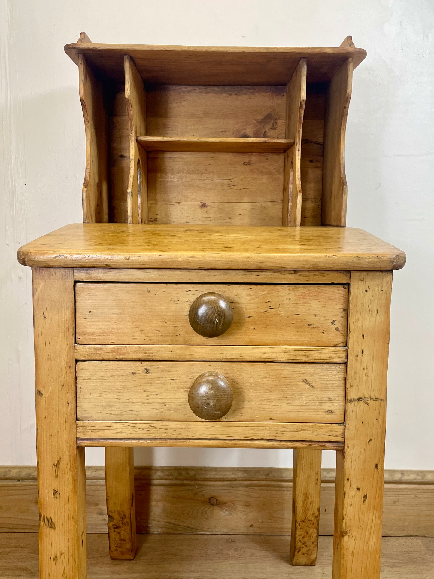 Wooden side table with two drawers and a shelf against a white wall.