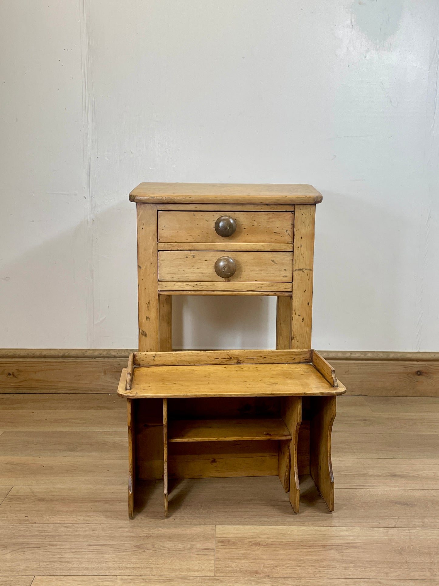Wooden side table with two drawers and an open shelf on a wooden floor.