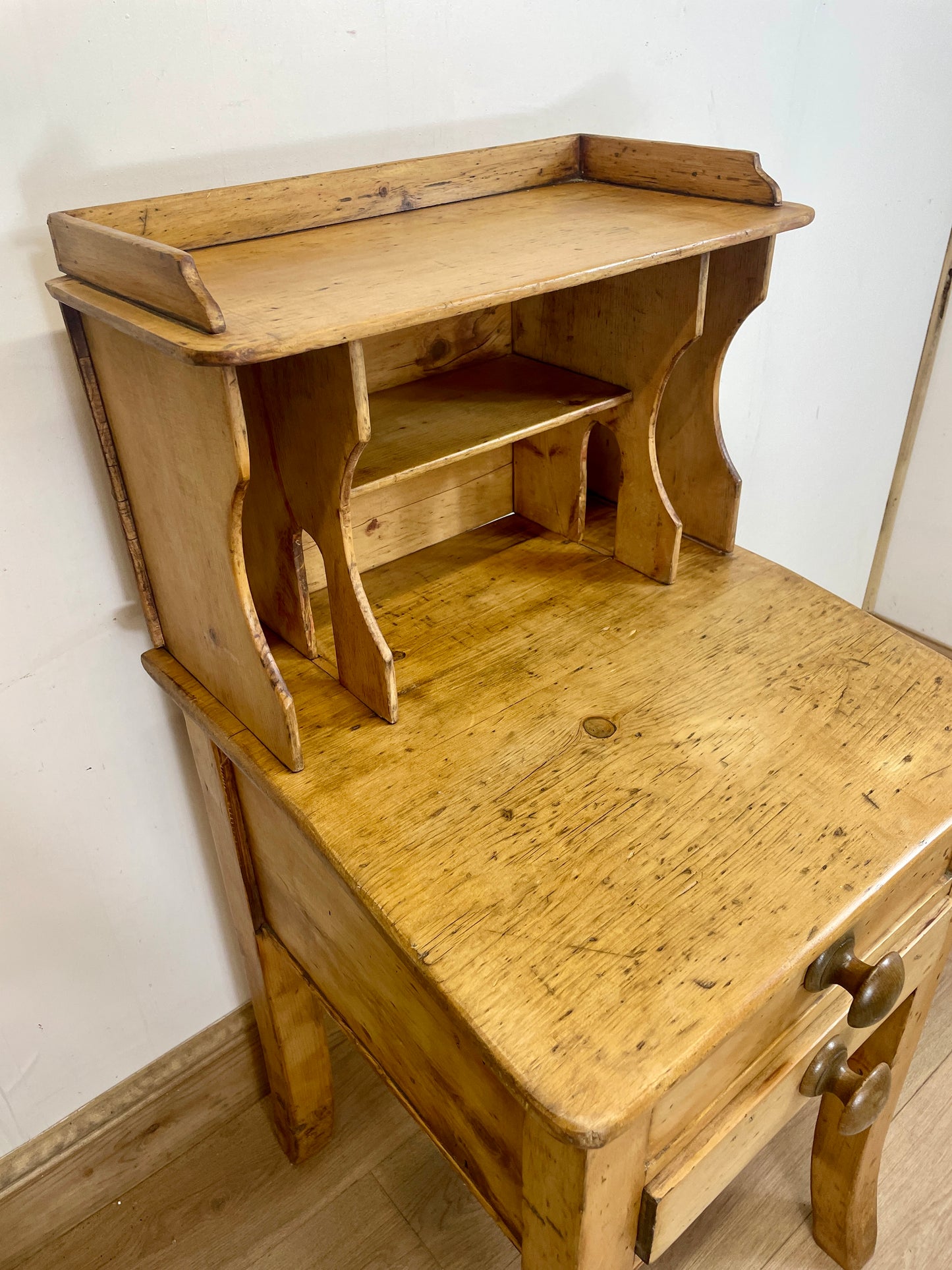 Wooden desk with a shelf against a white wall