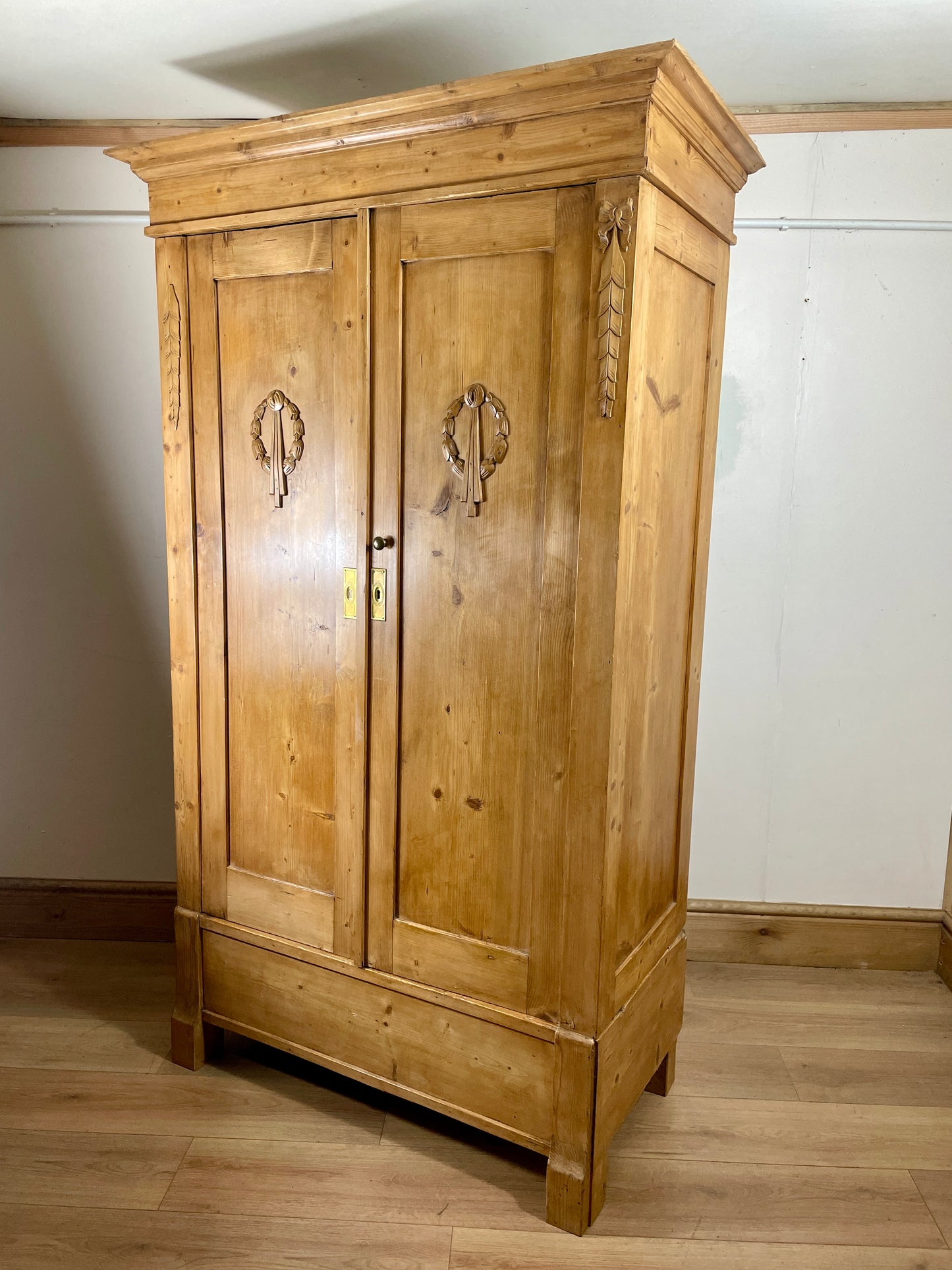 Wooden wardrobe with decorative elements on a wooden floor and white wall background