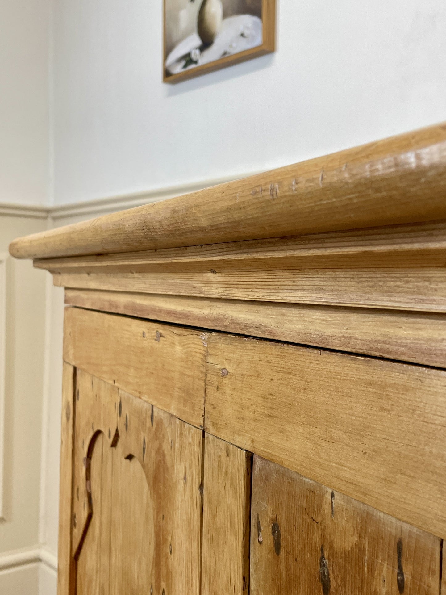 Wooden mantelpiece with a framed picture on a white wall