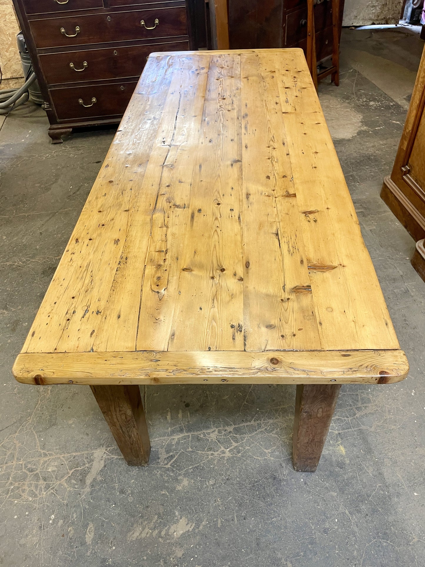 Wooden table with a rustic appearance on a concrete floor.
