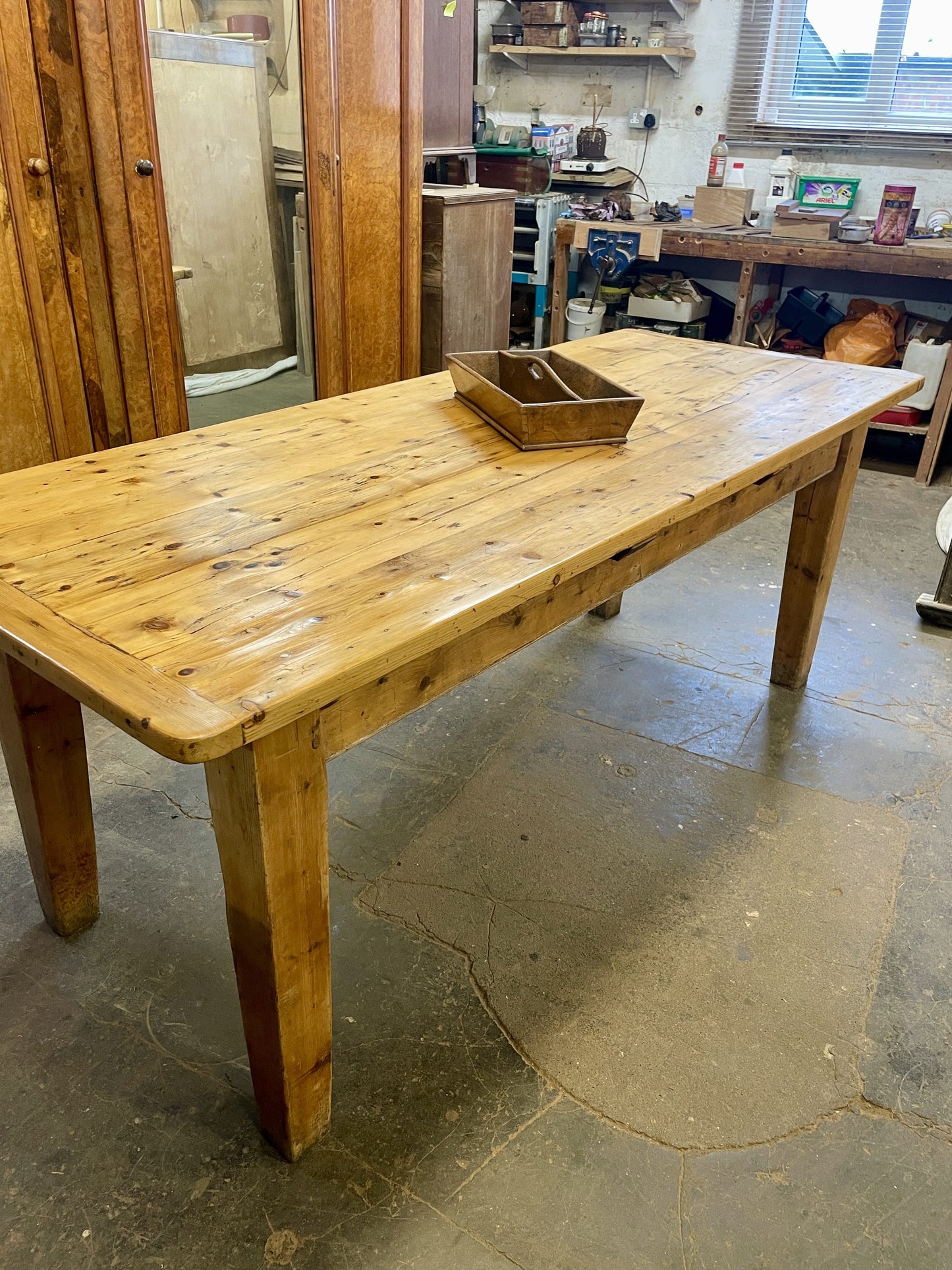 Wooden table in a workshop setting with tools and equipment in the background