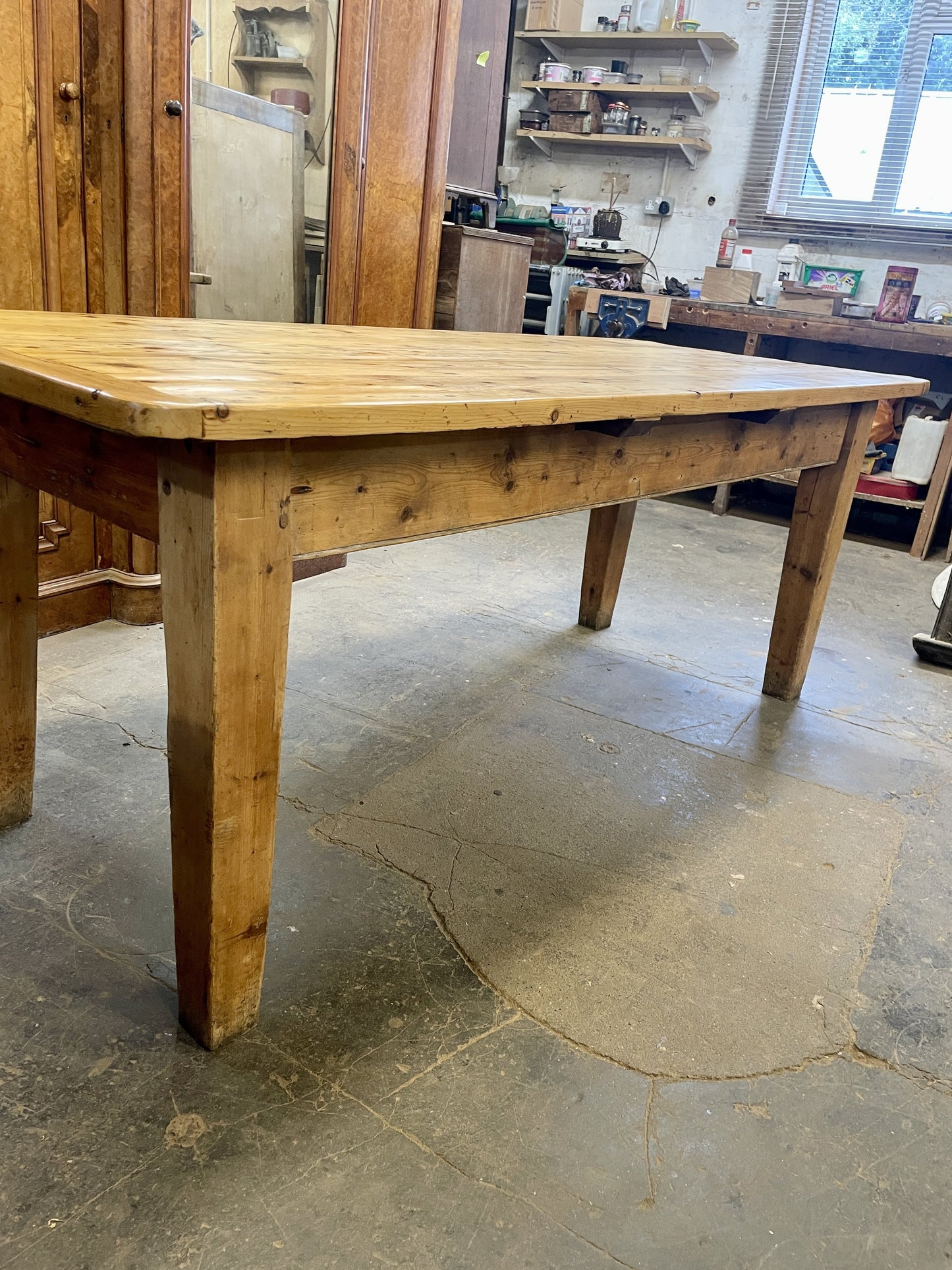 Wooden table in a workshop setting with tools and equipment in the background