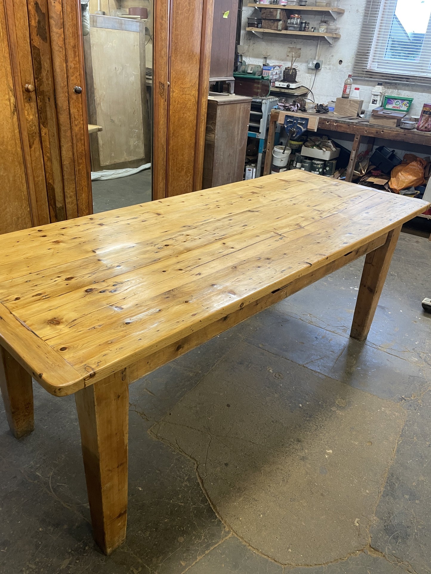 Wooden table in a workshop setting with tools and equipment in the background