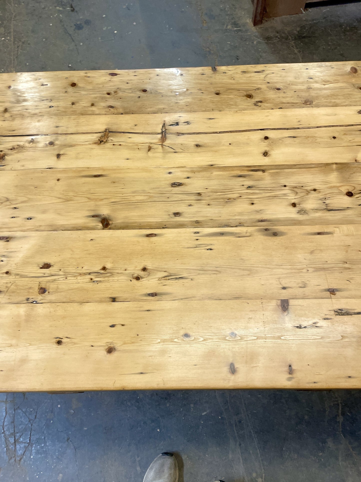 Wooden table with visible grain and knots on a concrete floor.