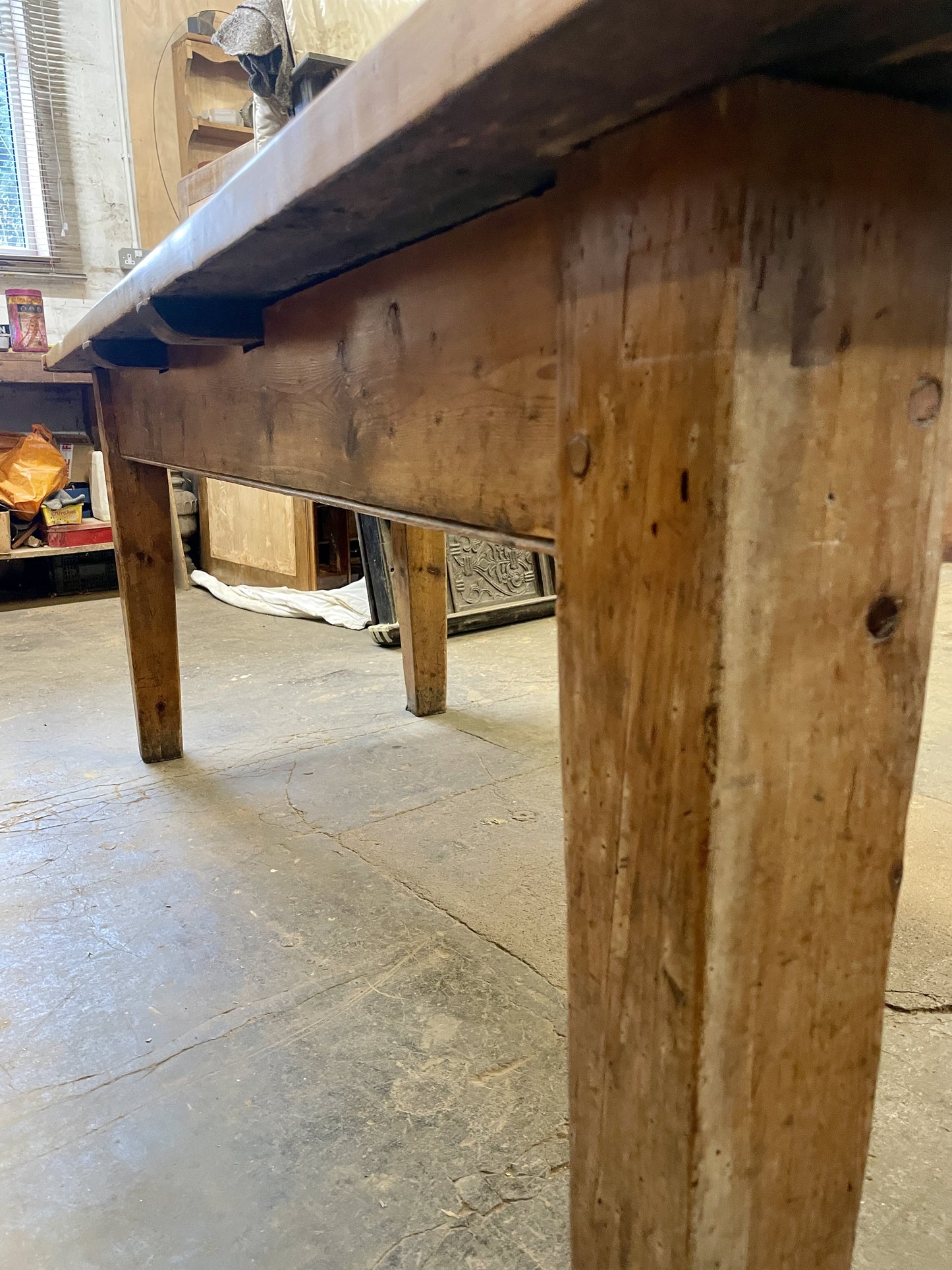 Close-up of a wooden table with a rustic appearance on a stone floor.
