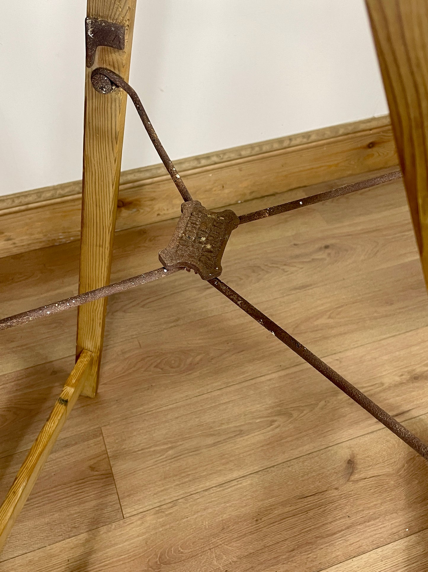 Rust-colored metal rod on a wooden floor with a white wall background