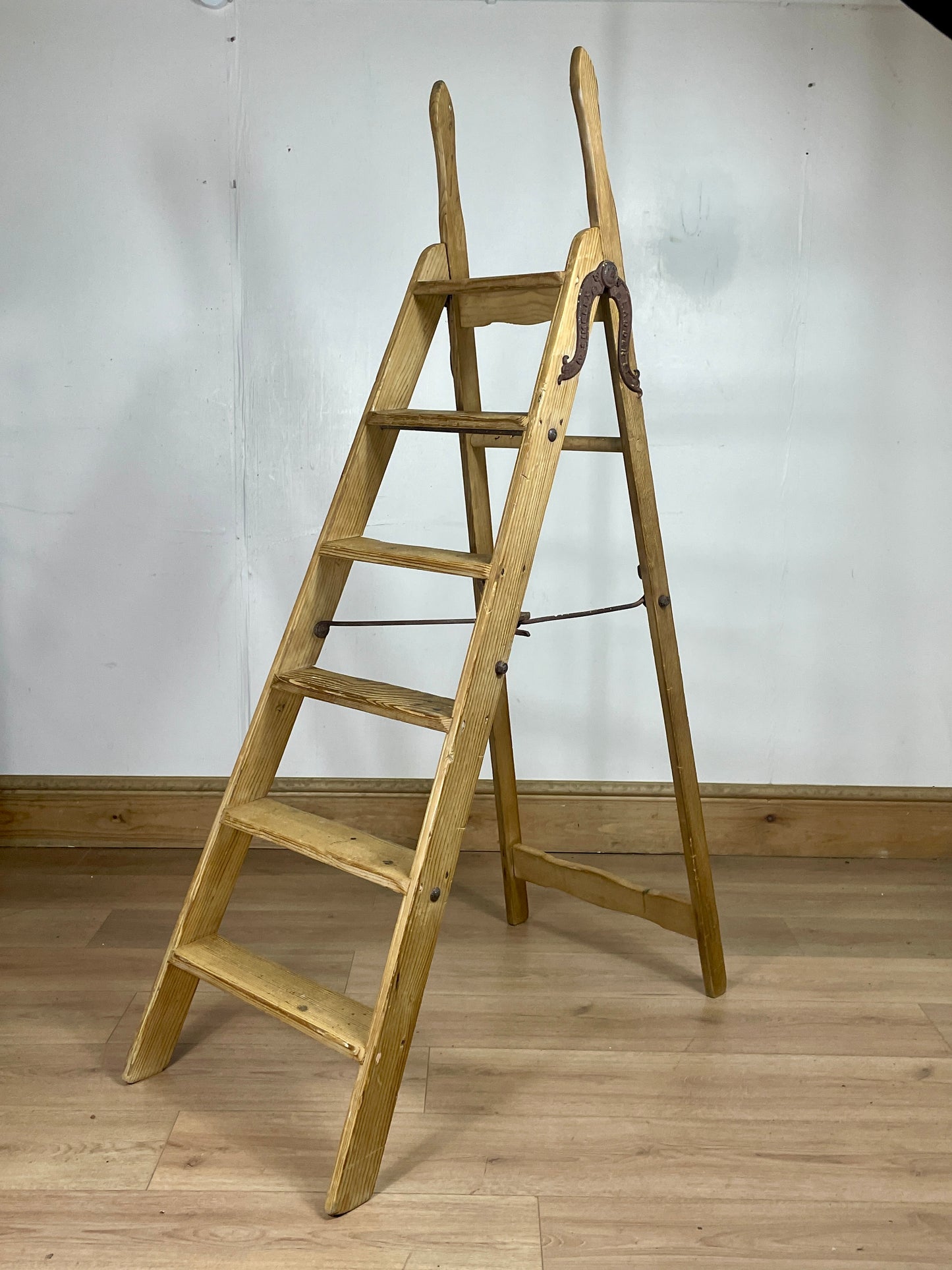 Wooden ladder against a white wall on a wooden floor