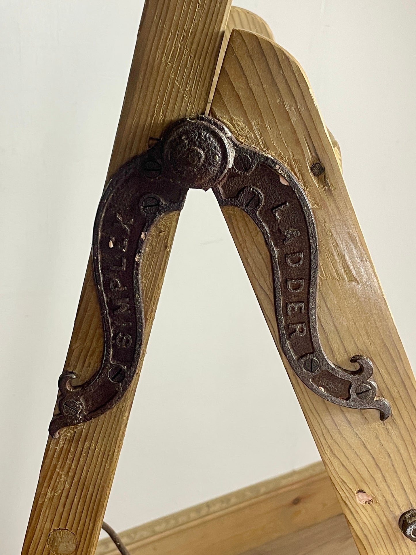 Wooden ladder with a metal hook on a plain background