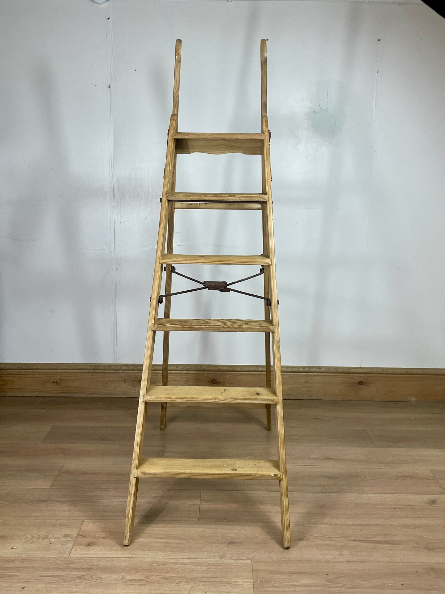 Wooden ladder against a white wall on a wooden floor