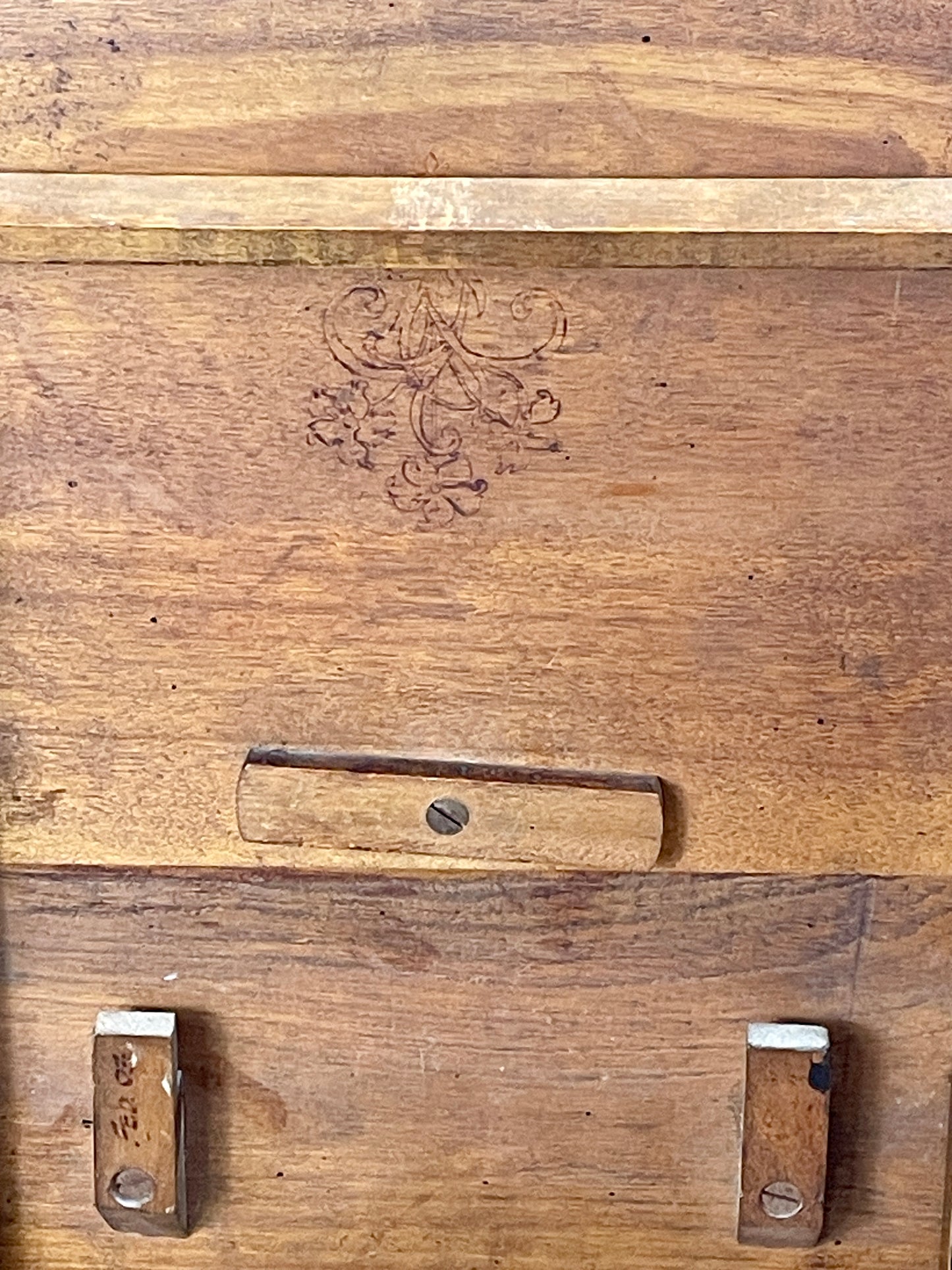 Close-up of a wooden surface with engraved design and metal fixtures.