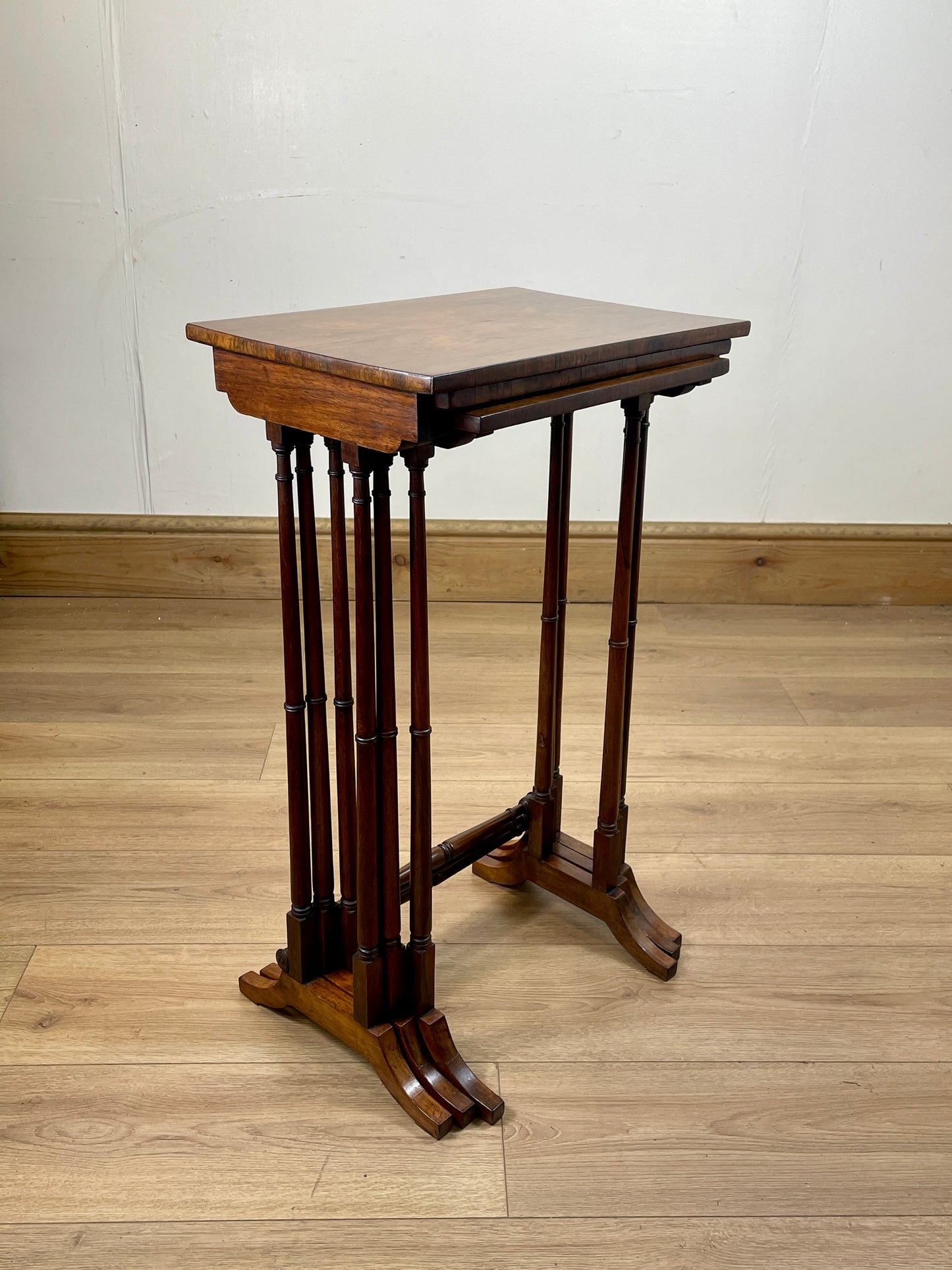 Wooden pedestal table on a wooden floor with a white wall background