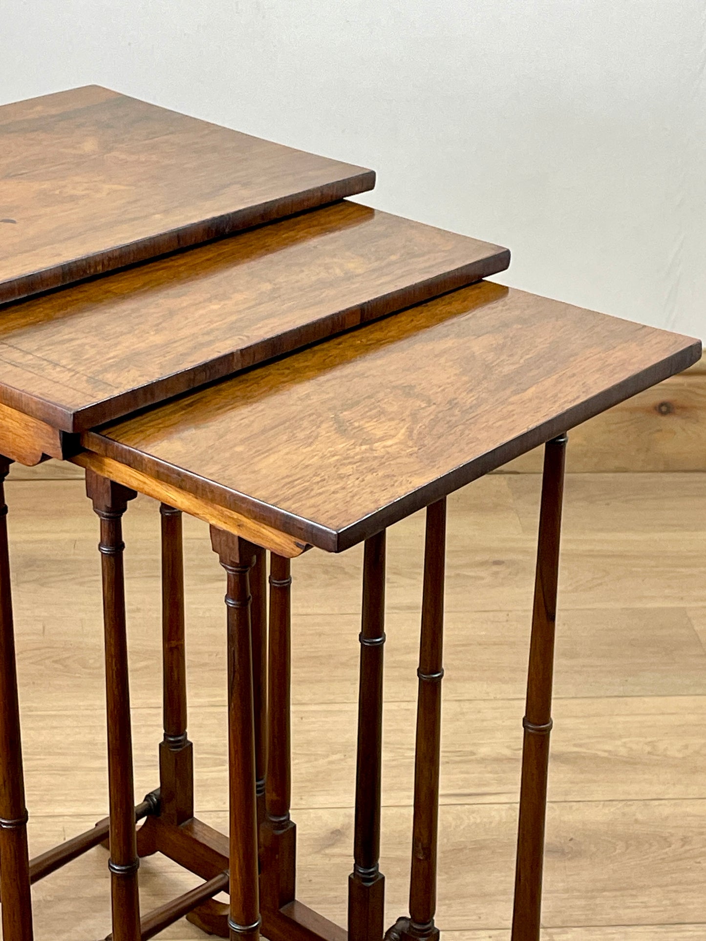 Set of three wooden nesting tables on a wooden floor.
