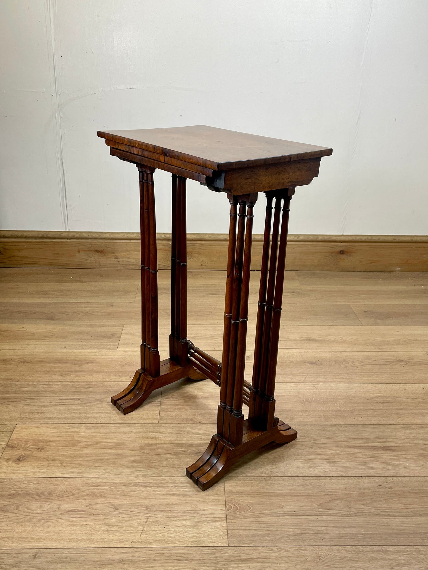 Wooden stand with a rectangular top on a wooden floor against a white wall