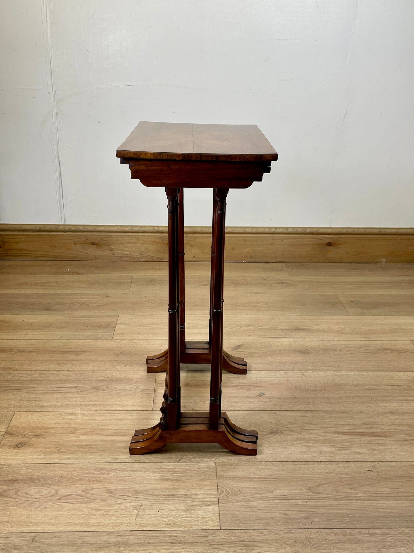 Wooden pedestal table on a wooden floor with a white wall background