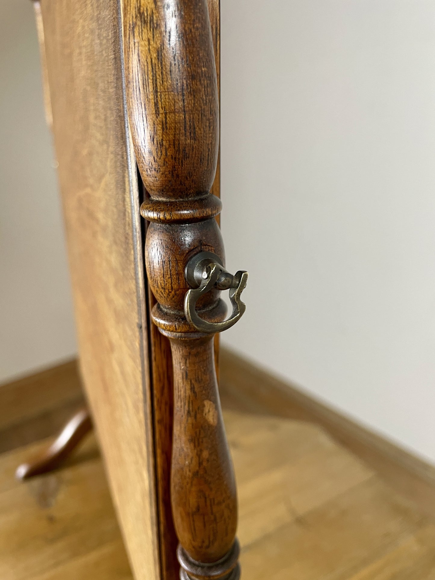 Wooden coat rack with a handle on a wooden floor.