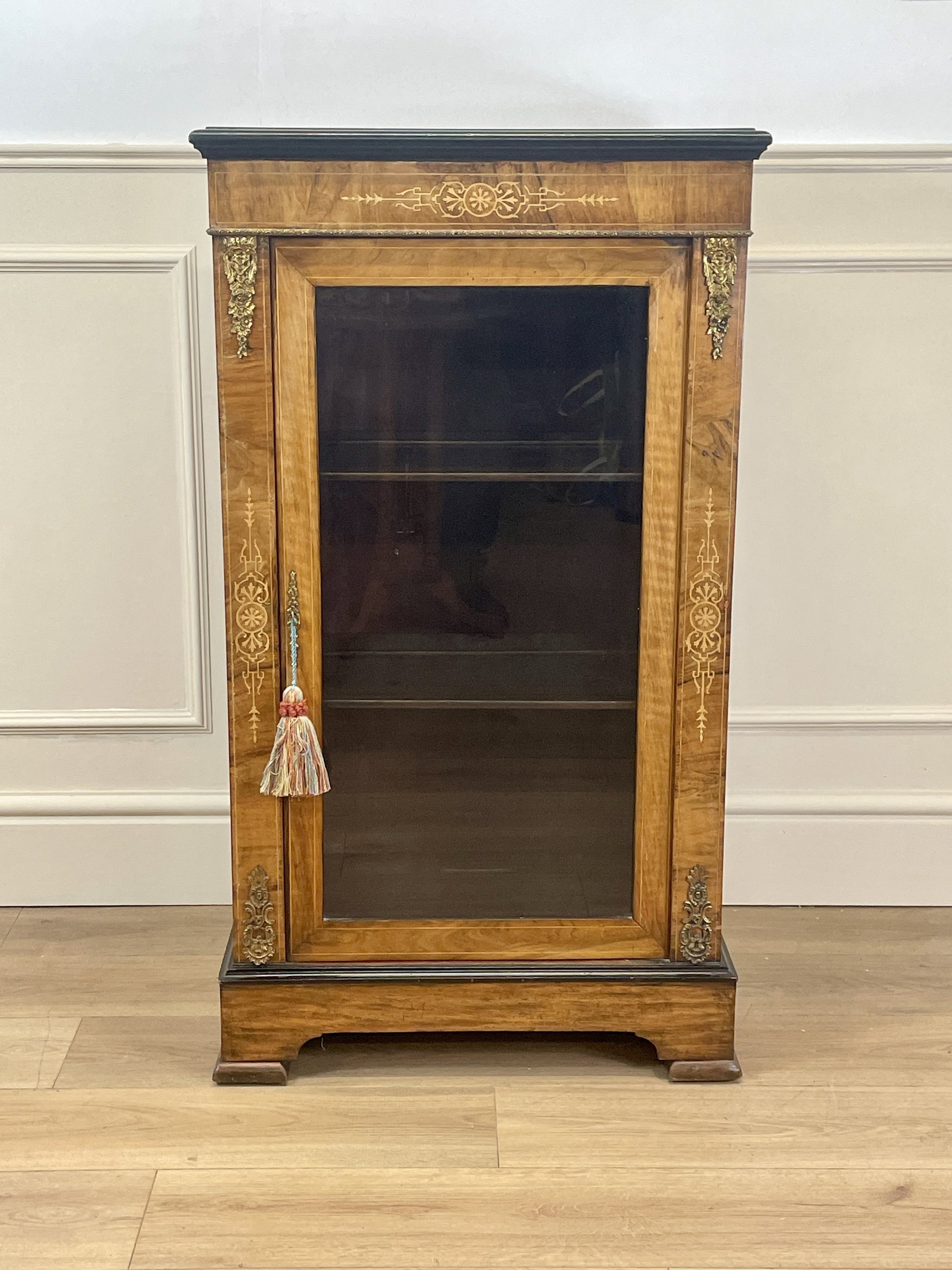 Wooden display cabinet with glass door against a white wall