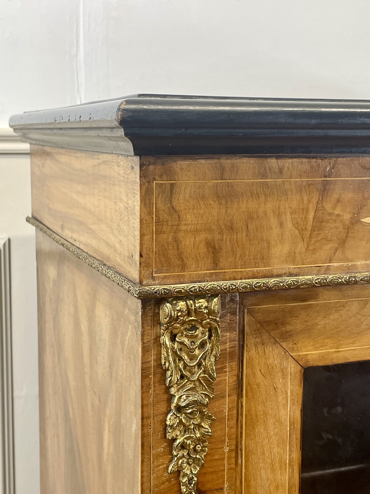 Wooden fireplace mantel with decorative carvings on a white wall.
