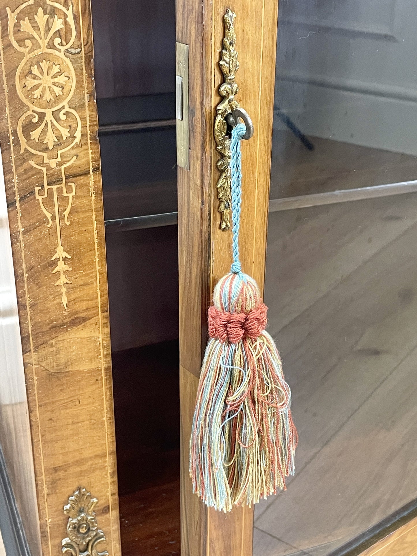 Decorative tassel hanging from a wooden wardrobe with intricate carvings.