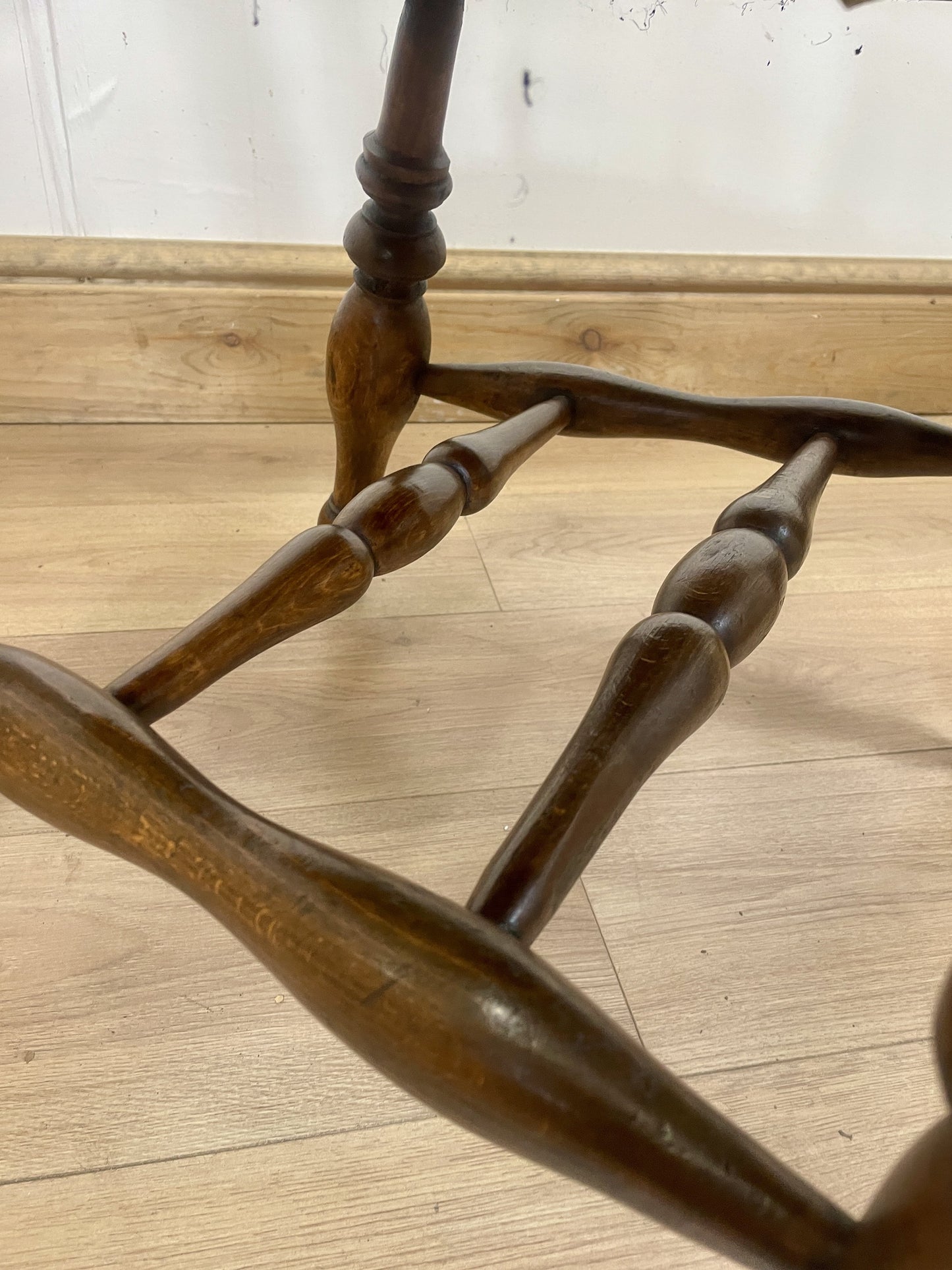 Wooden chair with intricate armrest design on a wooden floor.