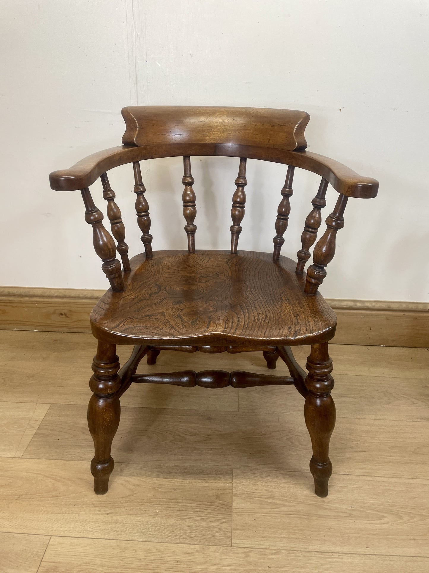 Wooden chair with spindle back and turned legs on a wooden floor.