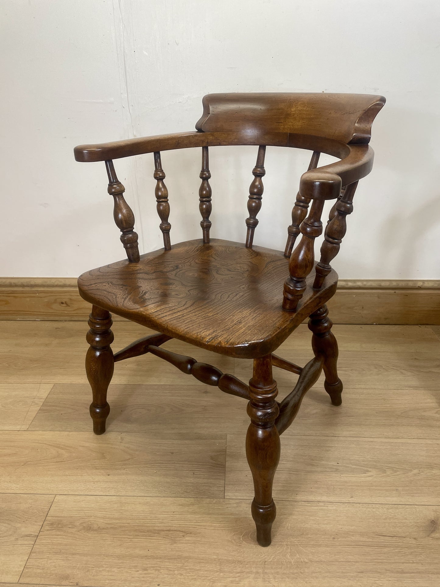Wooden chair with turned spindle back and seat on a wooden floor.