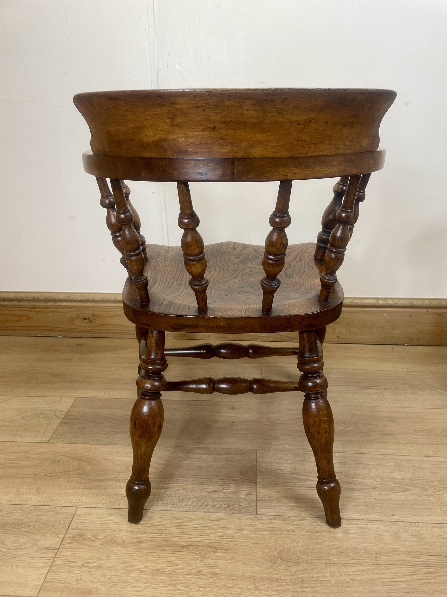 Wooden chair with turned legs on a wooden floor against a white wall