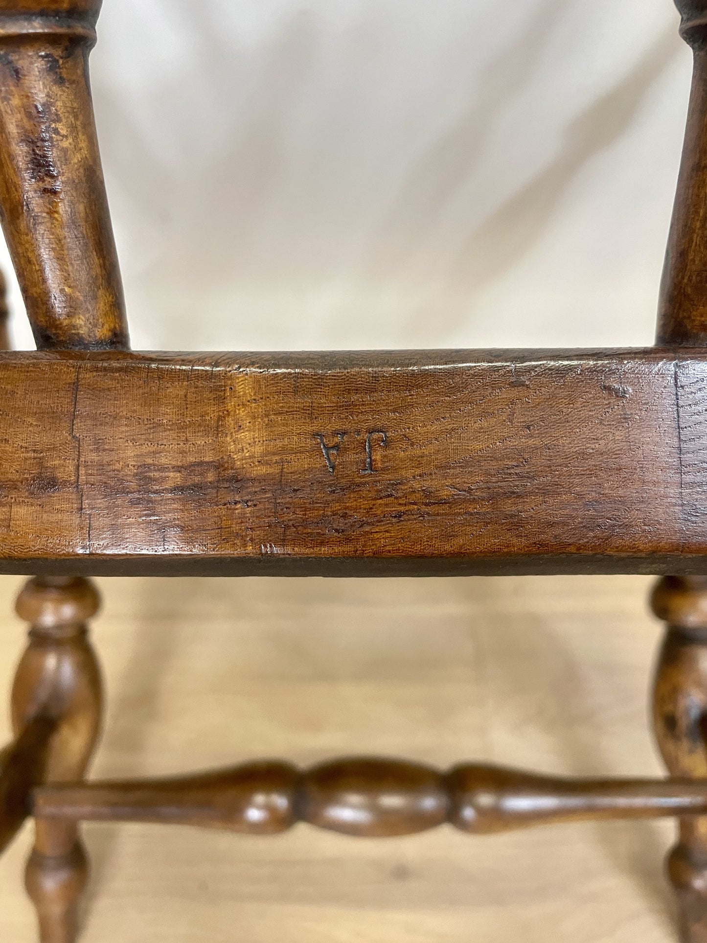 Close-up of a wooden chair with visible wear and a blurred background