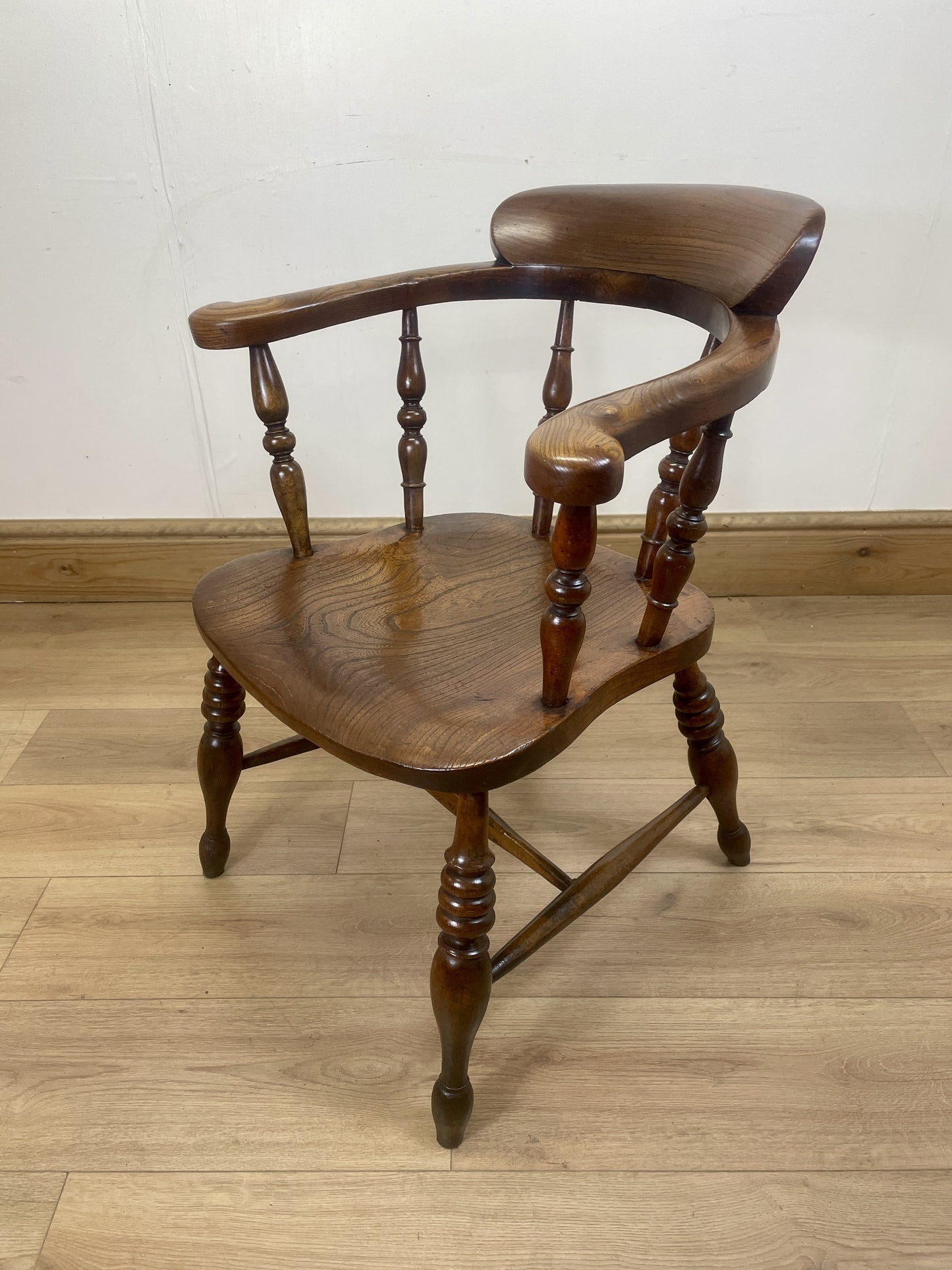 Wooden chair with curved backrest on a wooden floor against a white wall