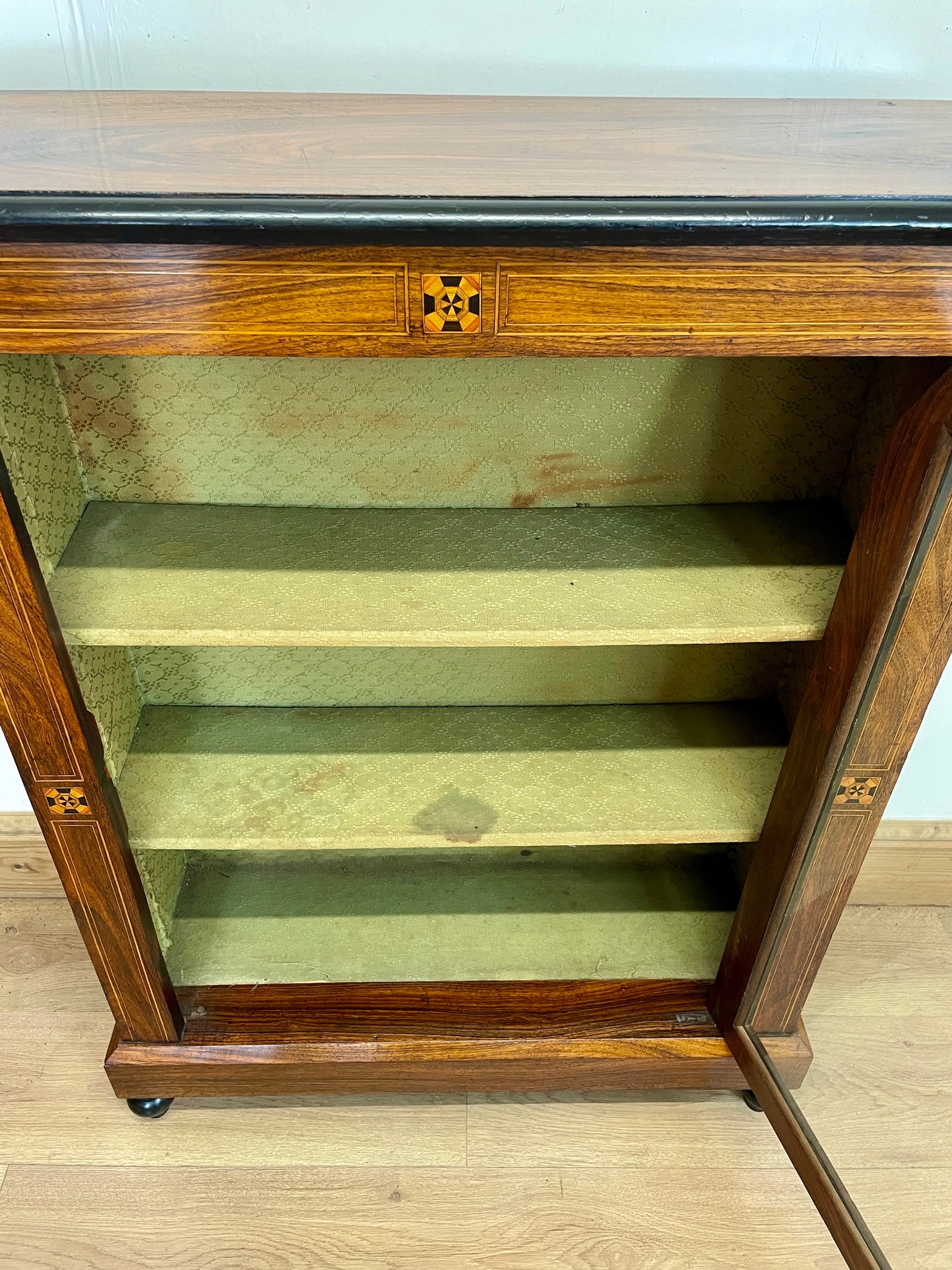 Wooden display cabinet with glass doors on a wooden floor.