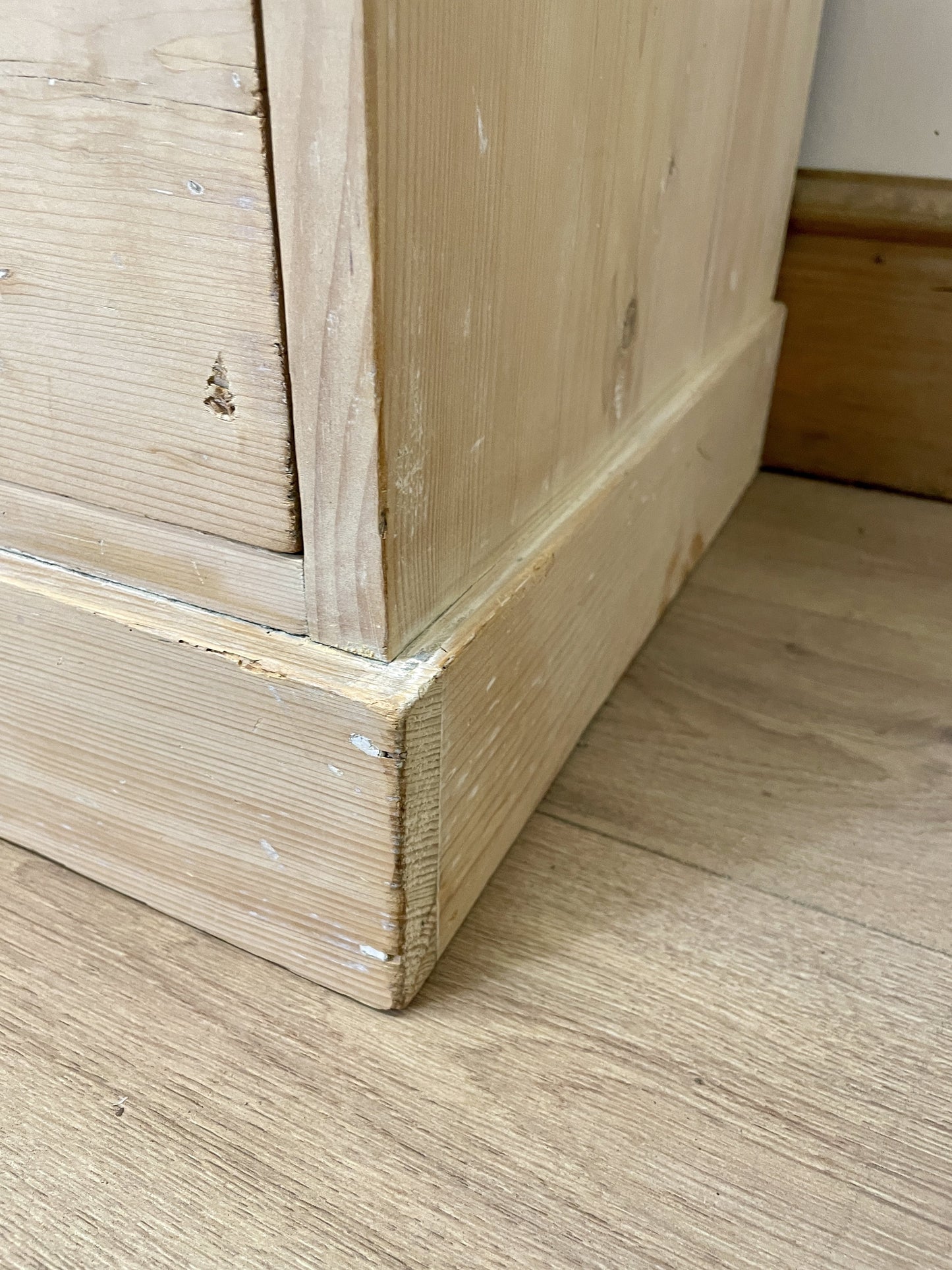Close-up of a wooden baseboard against a wooden floor.