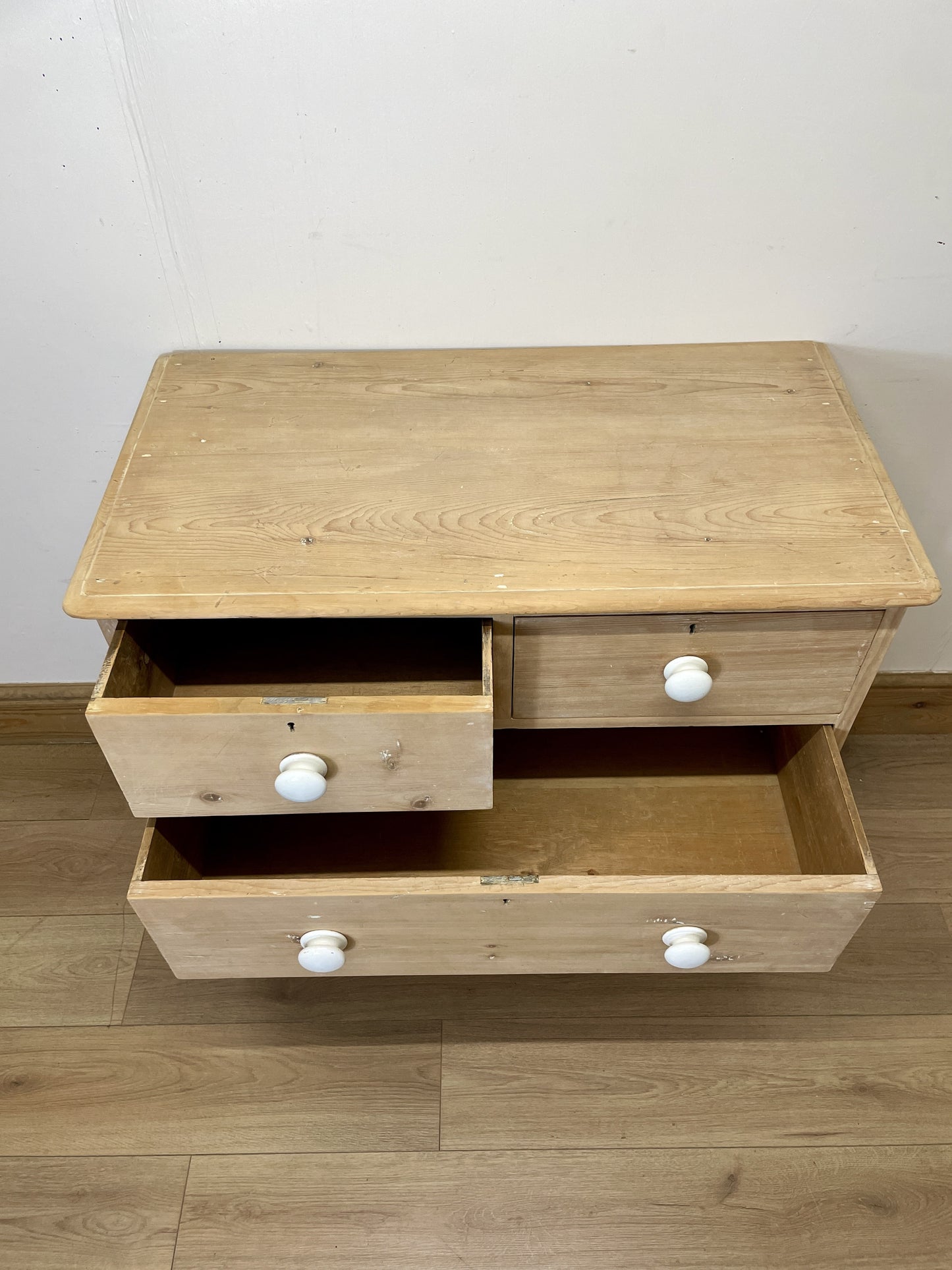 Wooden nightstand with two drawers and white knobs on a wooden floor.