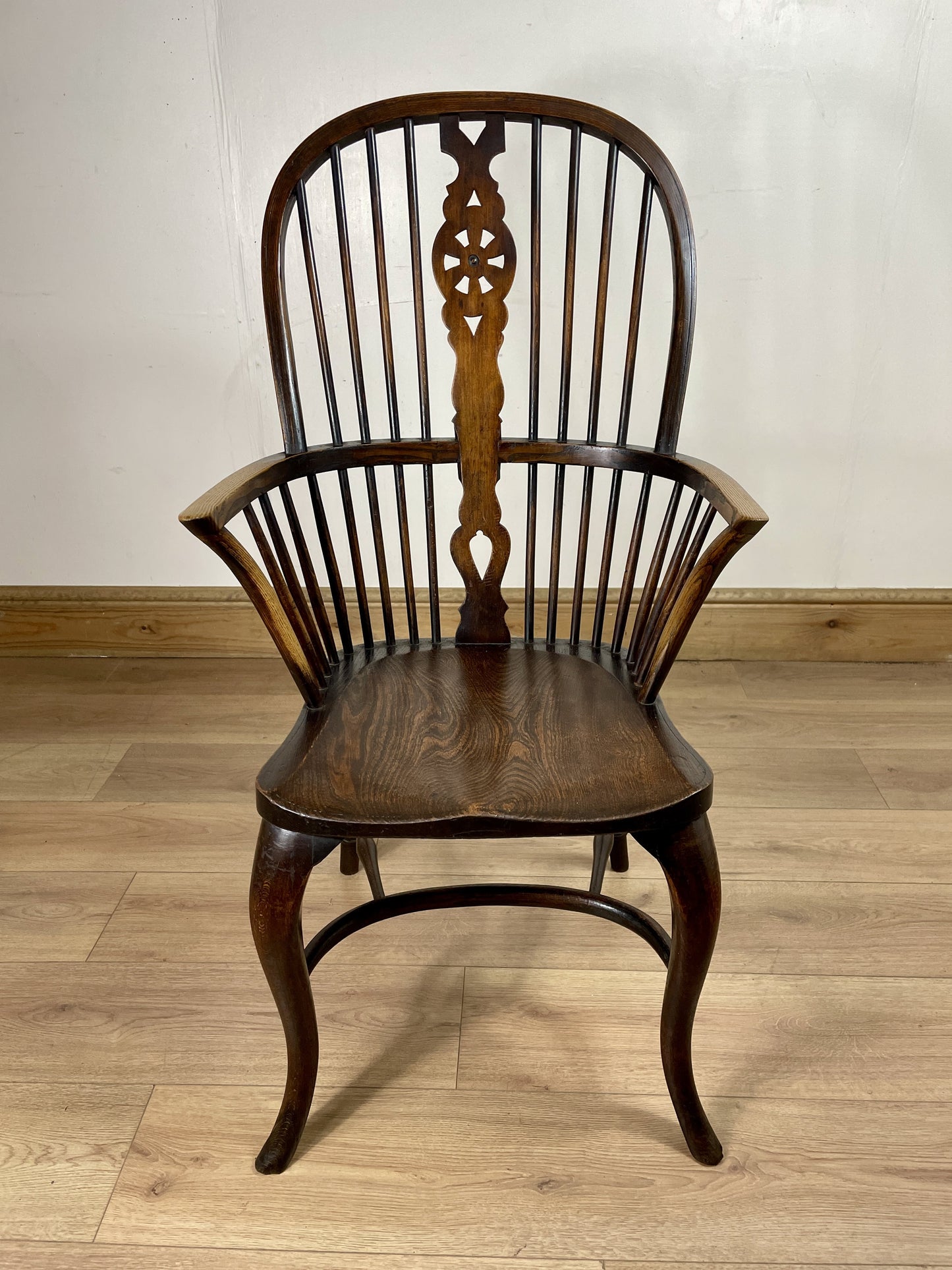 Wooden chair with intricate back design on a wooden floor.
