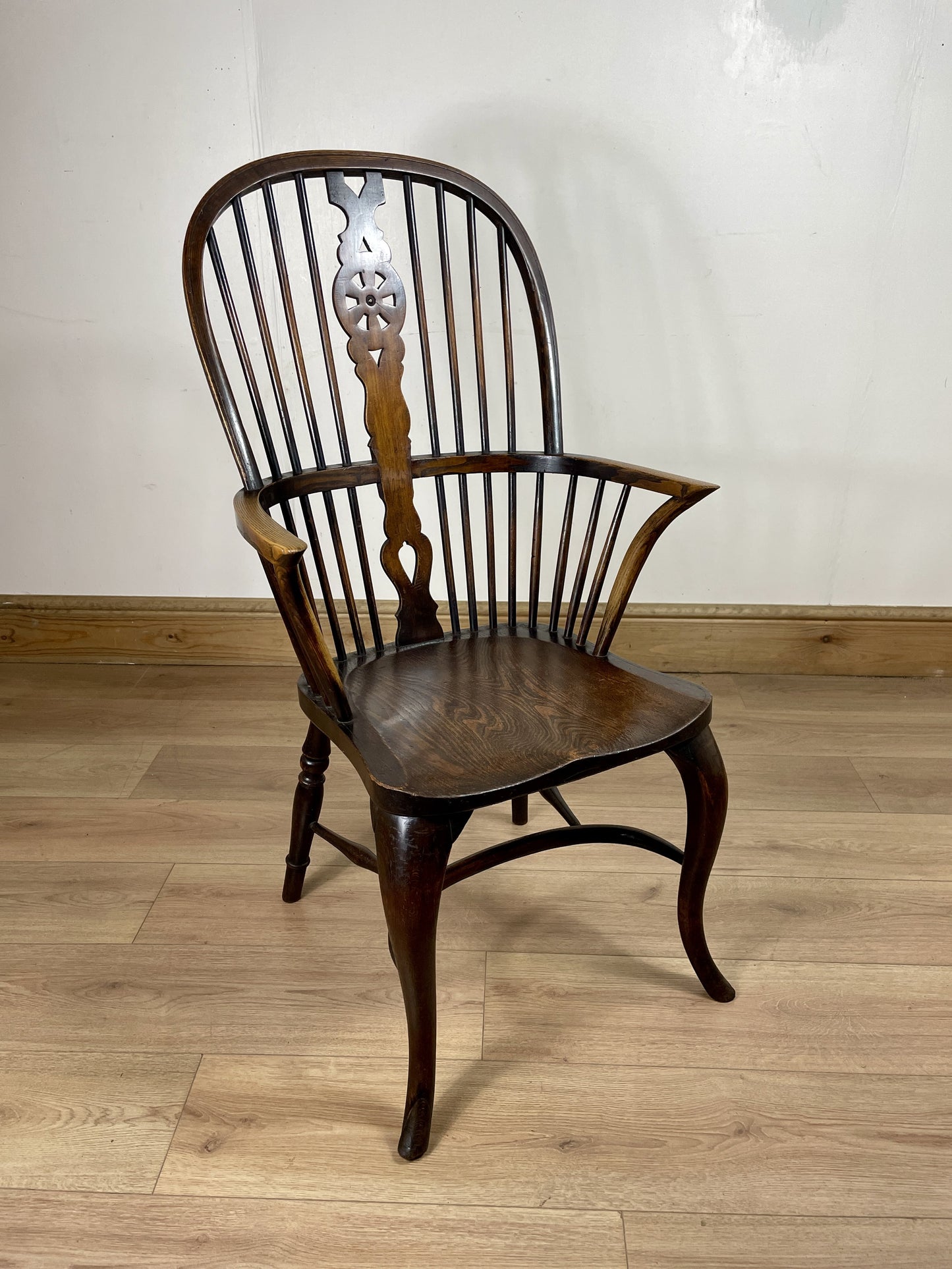 Wooden chair with a decorative backrest on a wooden floor.