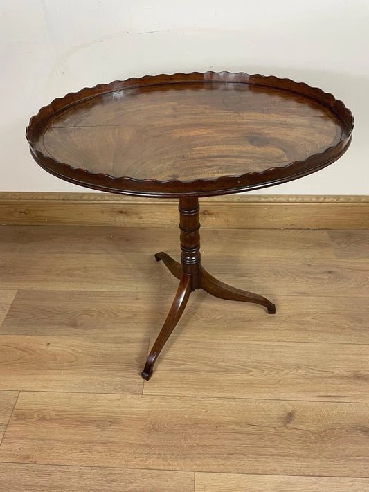 Wooden round table with scalloped edge on a wooden floor.