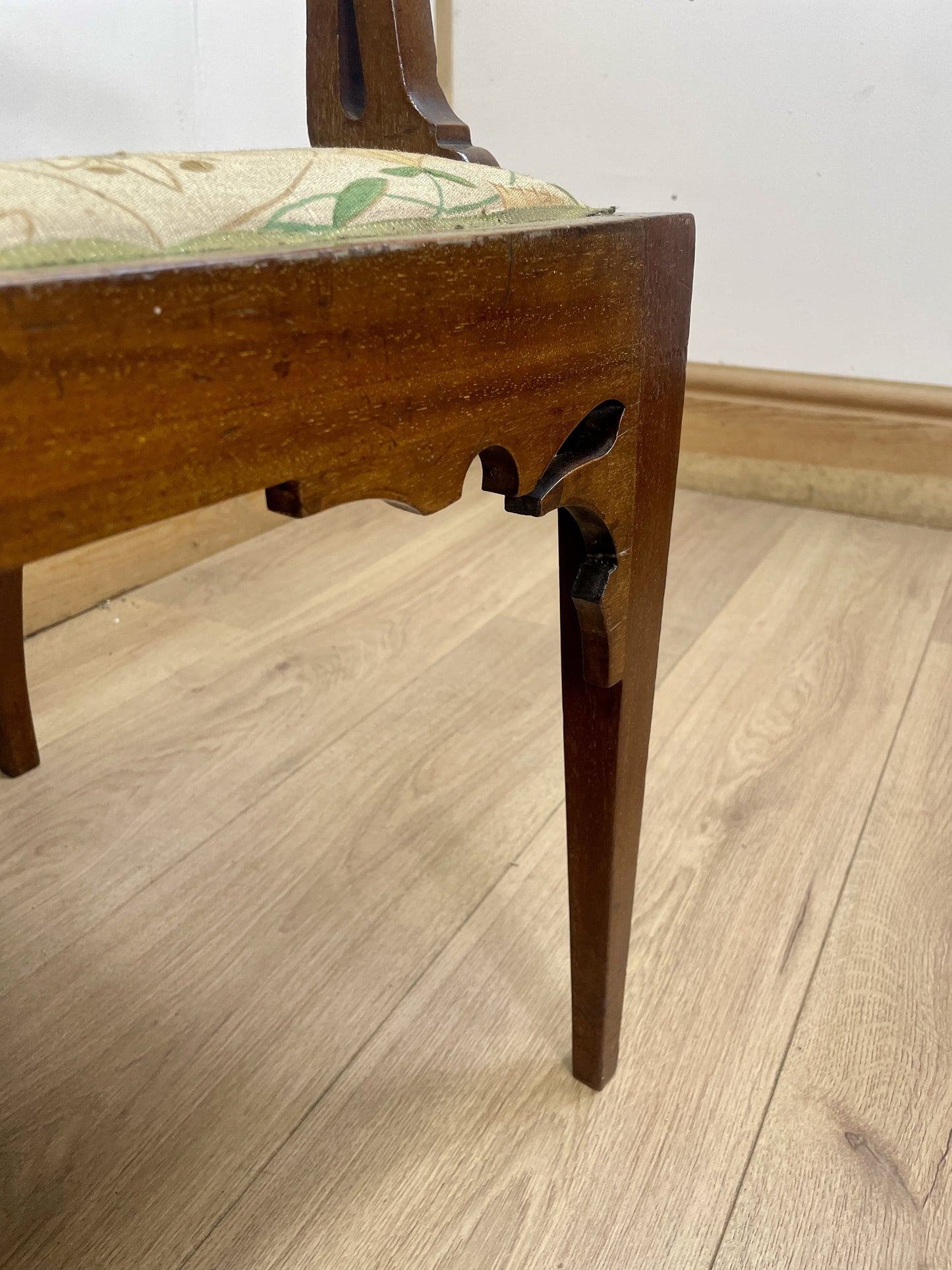 Wooden chair leg on a wooden floor with a plain wall background