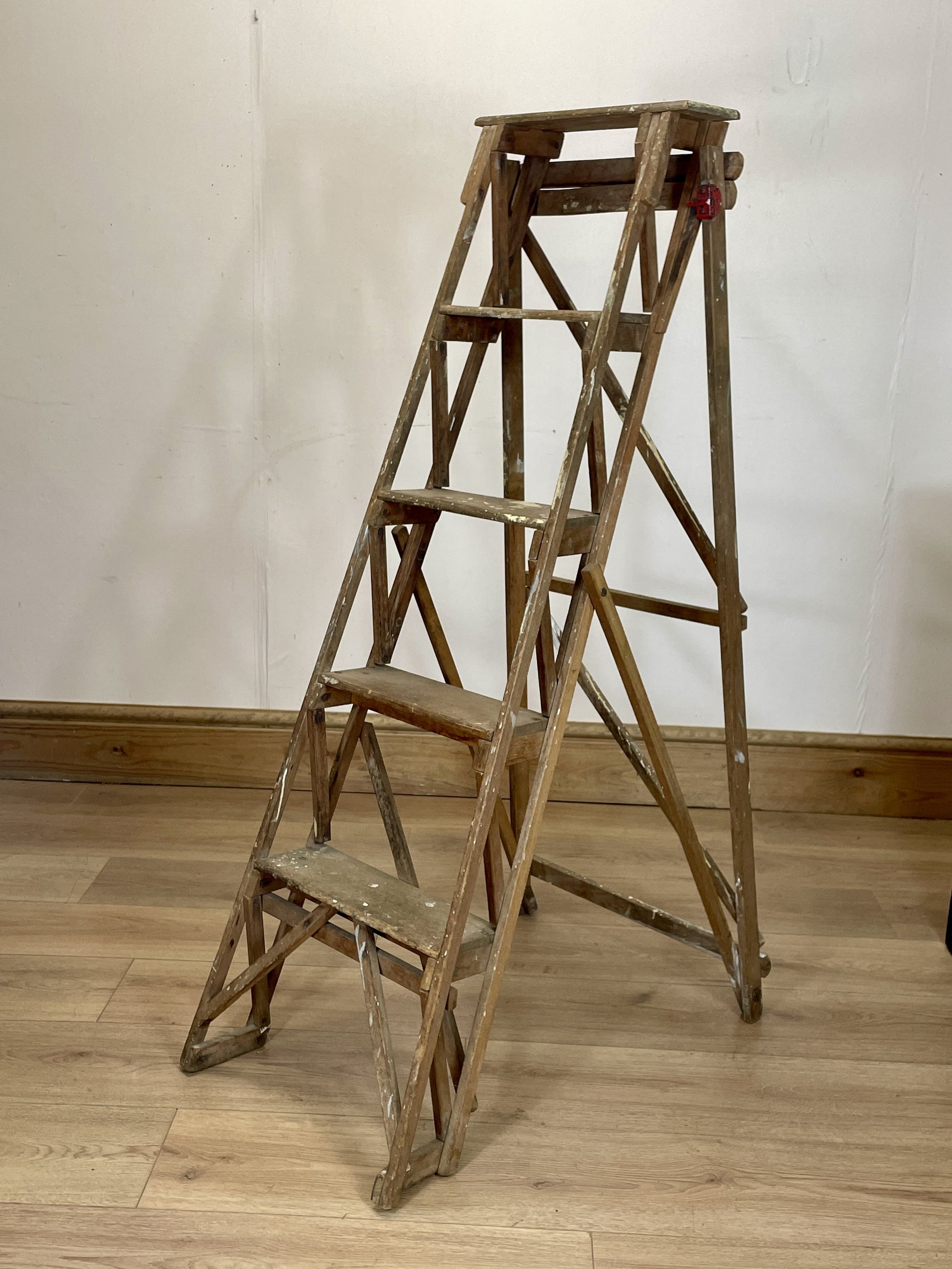 Wooden step ladder on a wooden floor against a white wall