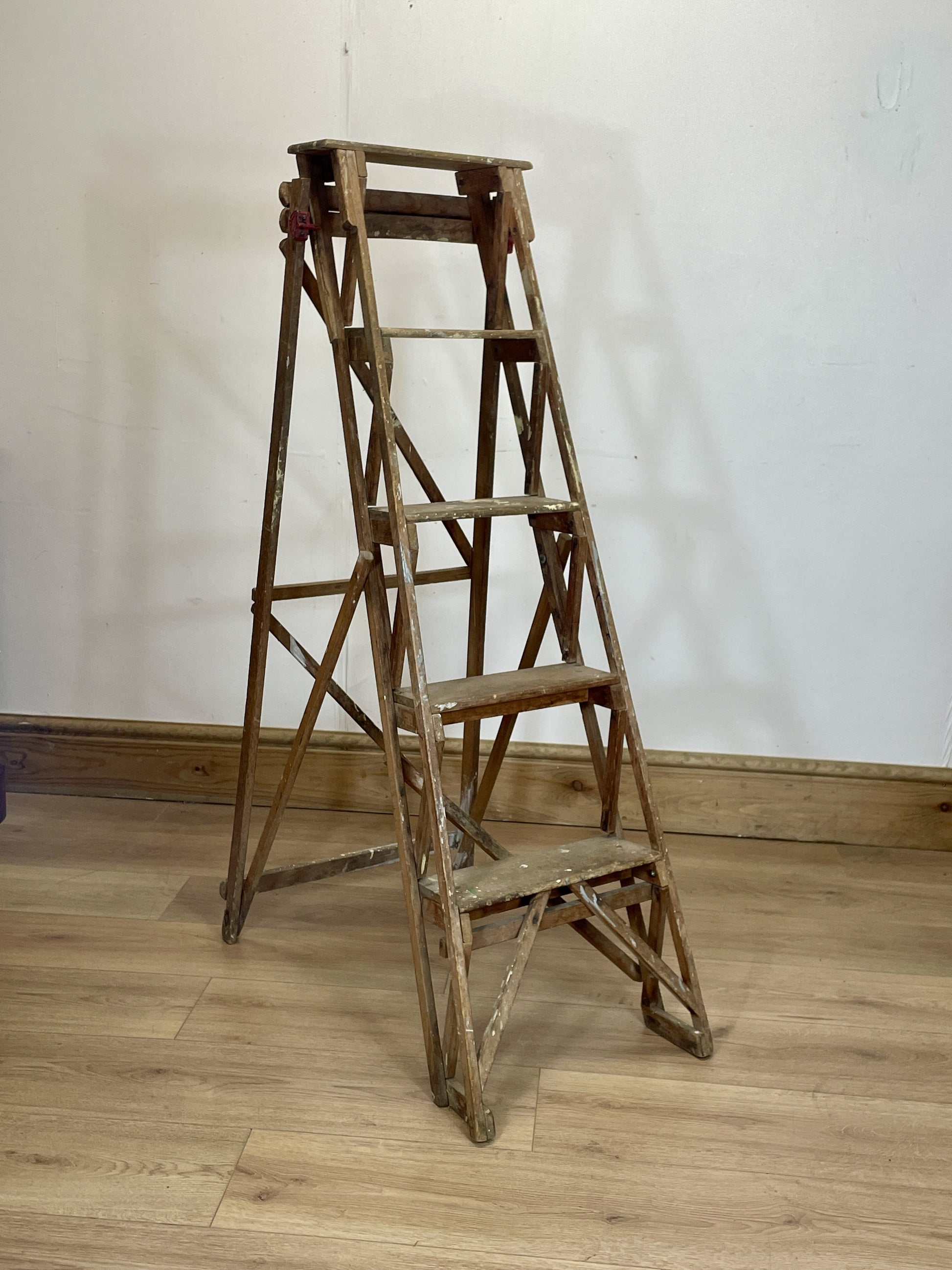 Wooden step ladder against a white wall on a wooden floor