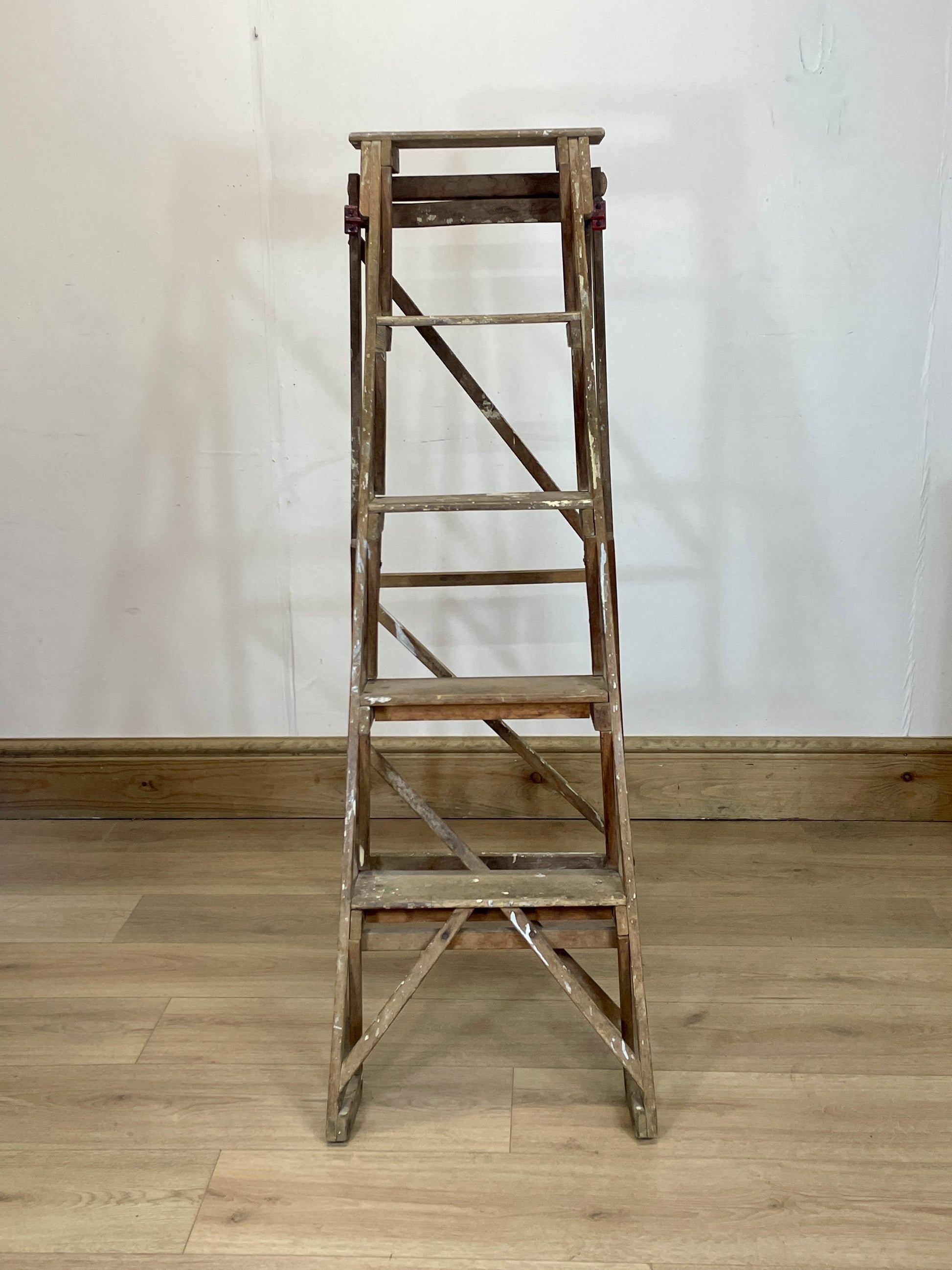 Wooden ladder on a wooden floor with a white wall background