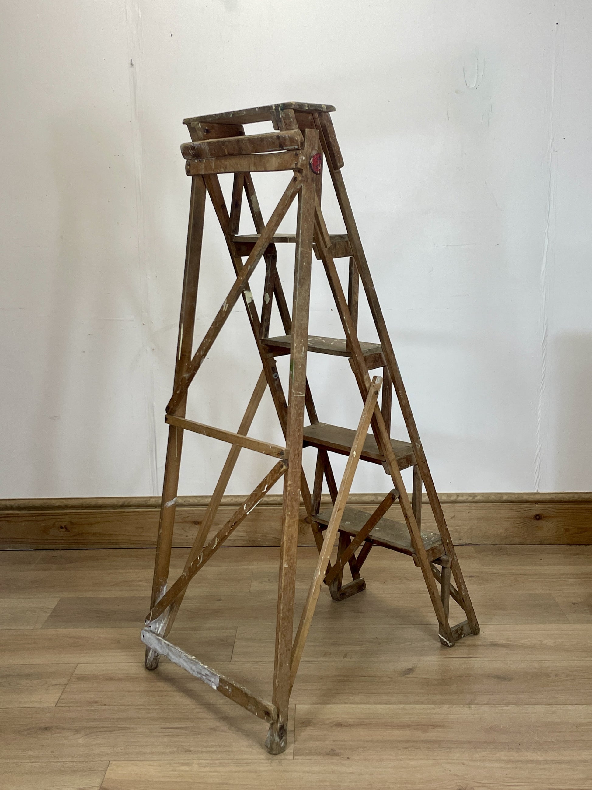 Wooden step ladder on a wooden floor with a white wall background
