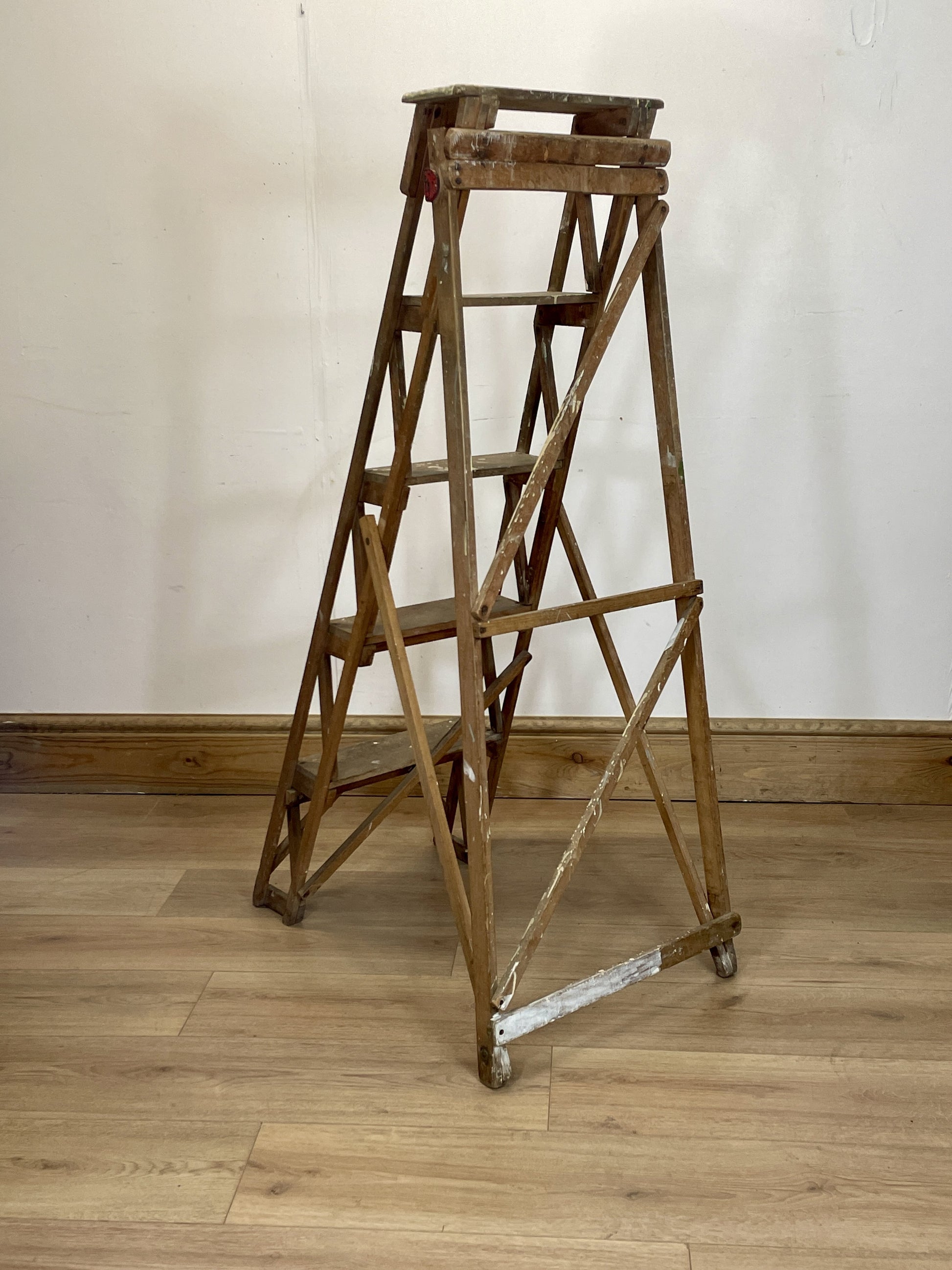 Wooden step ladder on a wooden floor with a white wall background
